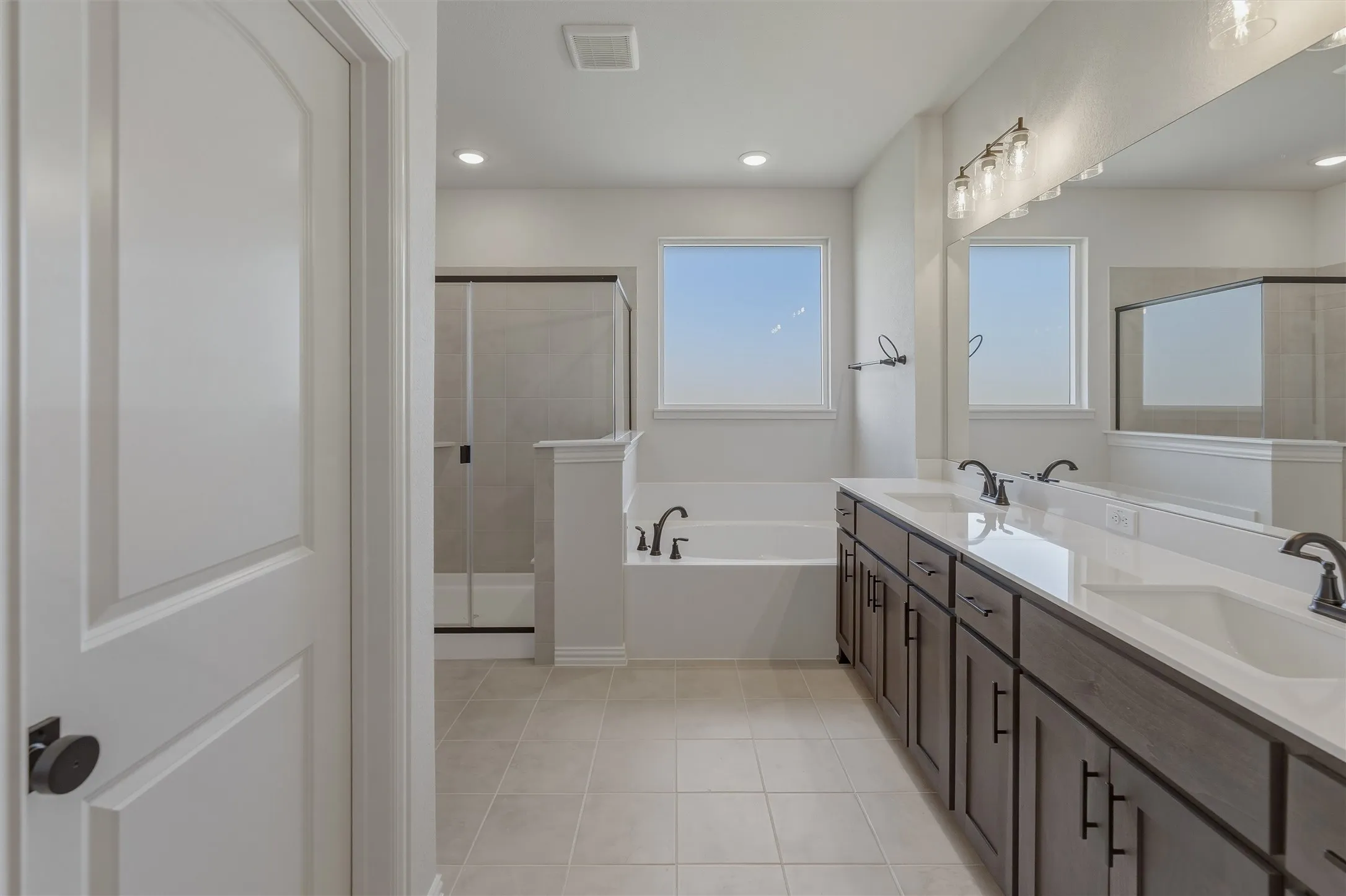 Bathroom featuring a dual vanity with dark wood cabinetry, white countertops, and black hardware