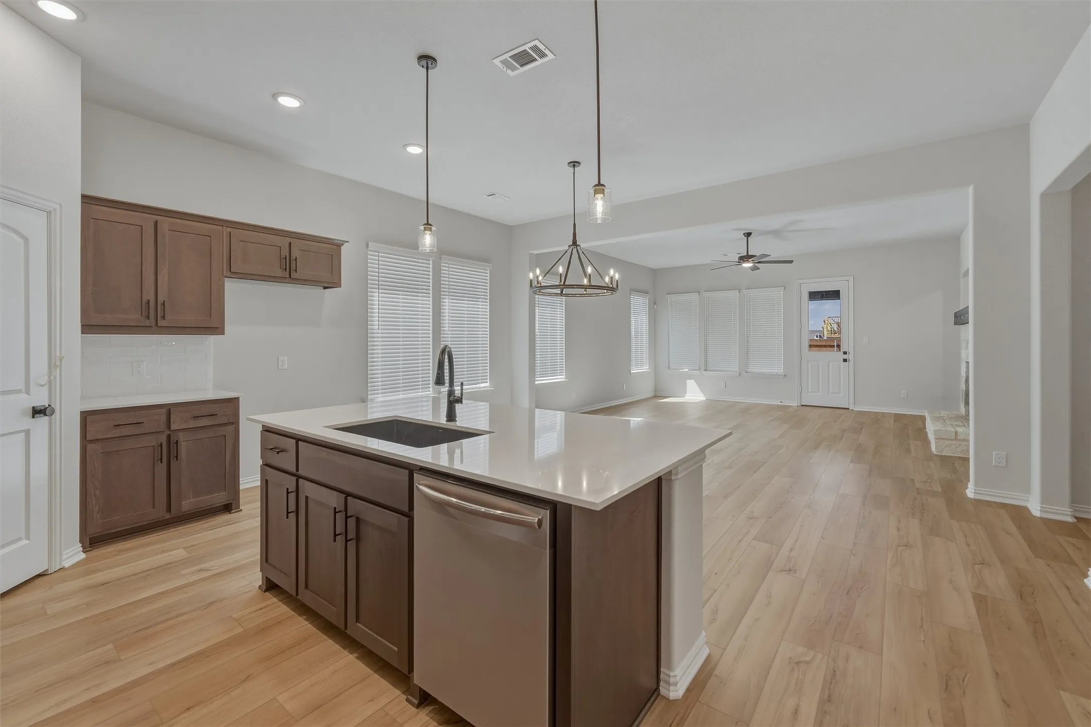 Kitchen island with an undermount sink, integrated dishwasher, and a light-toned countertop