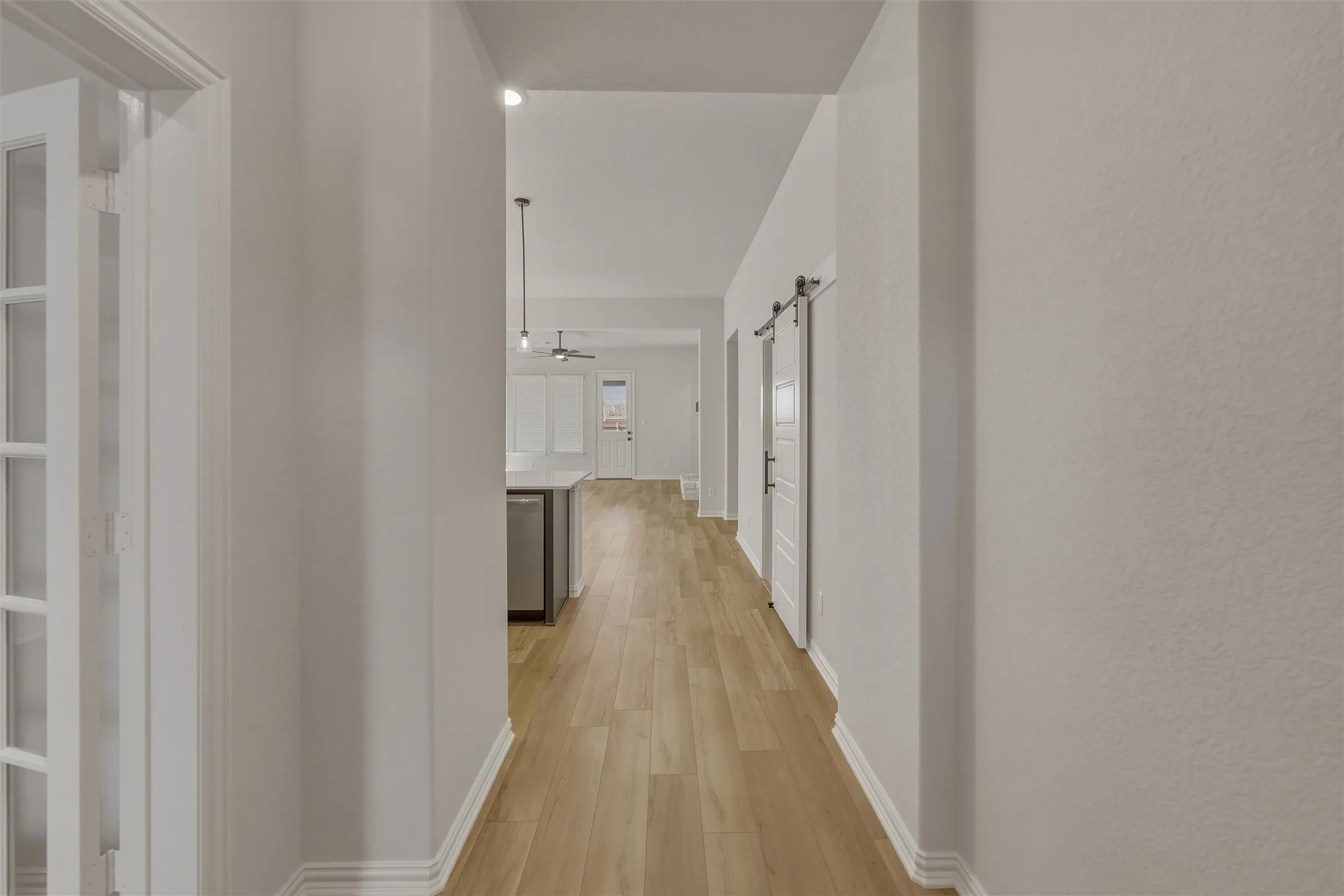 Hallway featuring wood-finish flooring, white baseboards, and light-toned walls