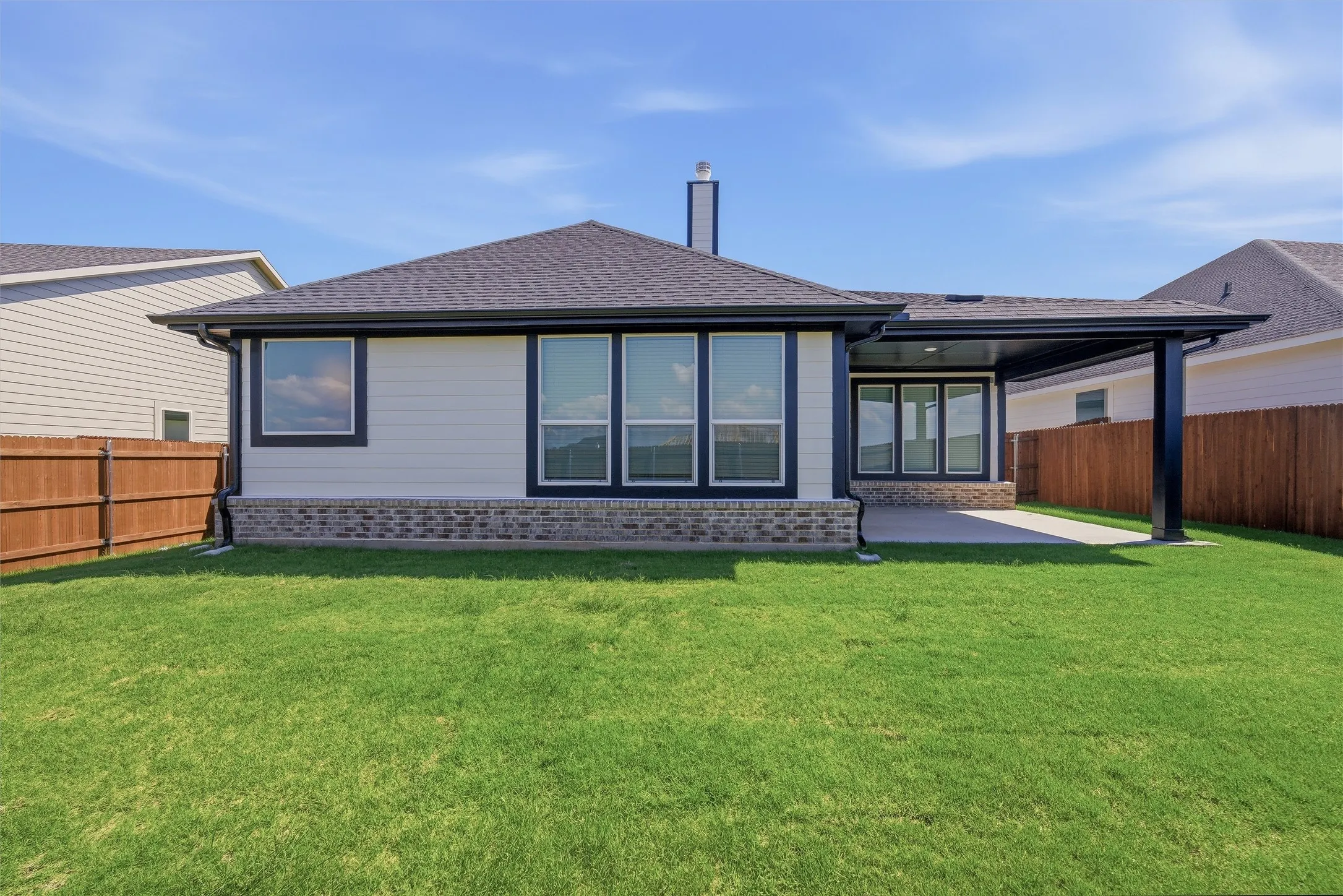 Expansive backyard featuring a covered patio, multiple windows, brick veneer, and a privacy fence