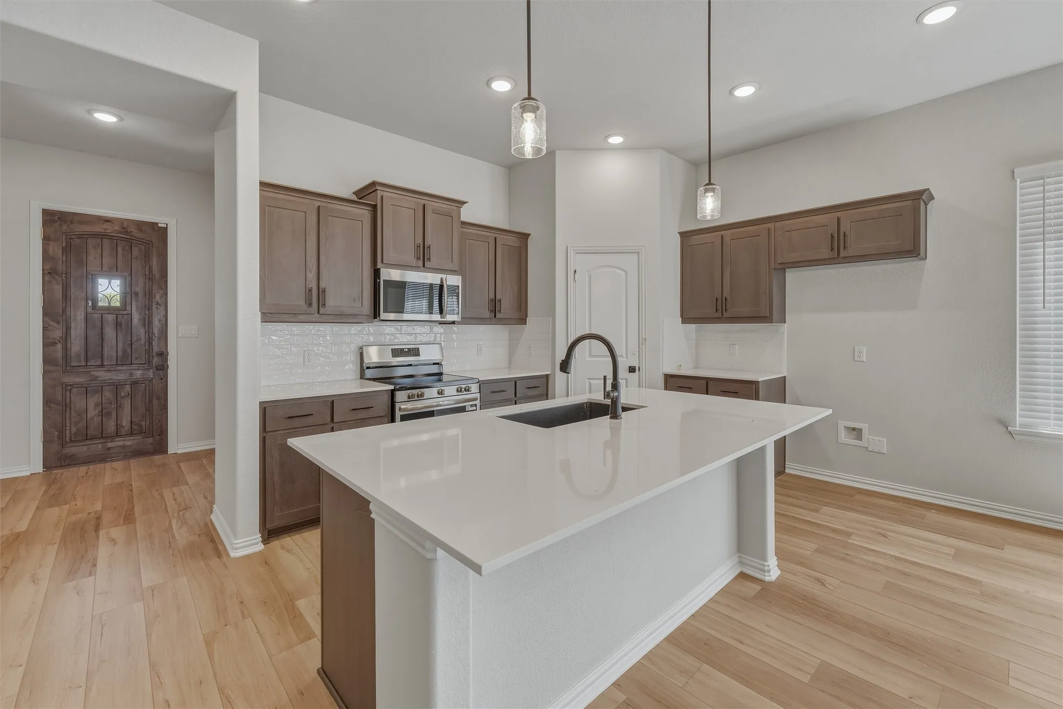 Kitchen featuring a center island with sink, white countertops, stainless steel appliances, subway tile backsplash, and recessed lighting