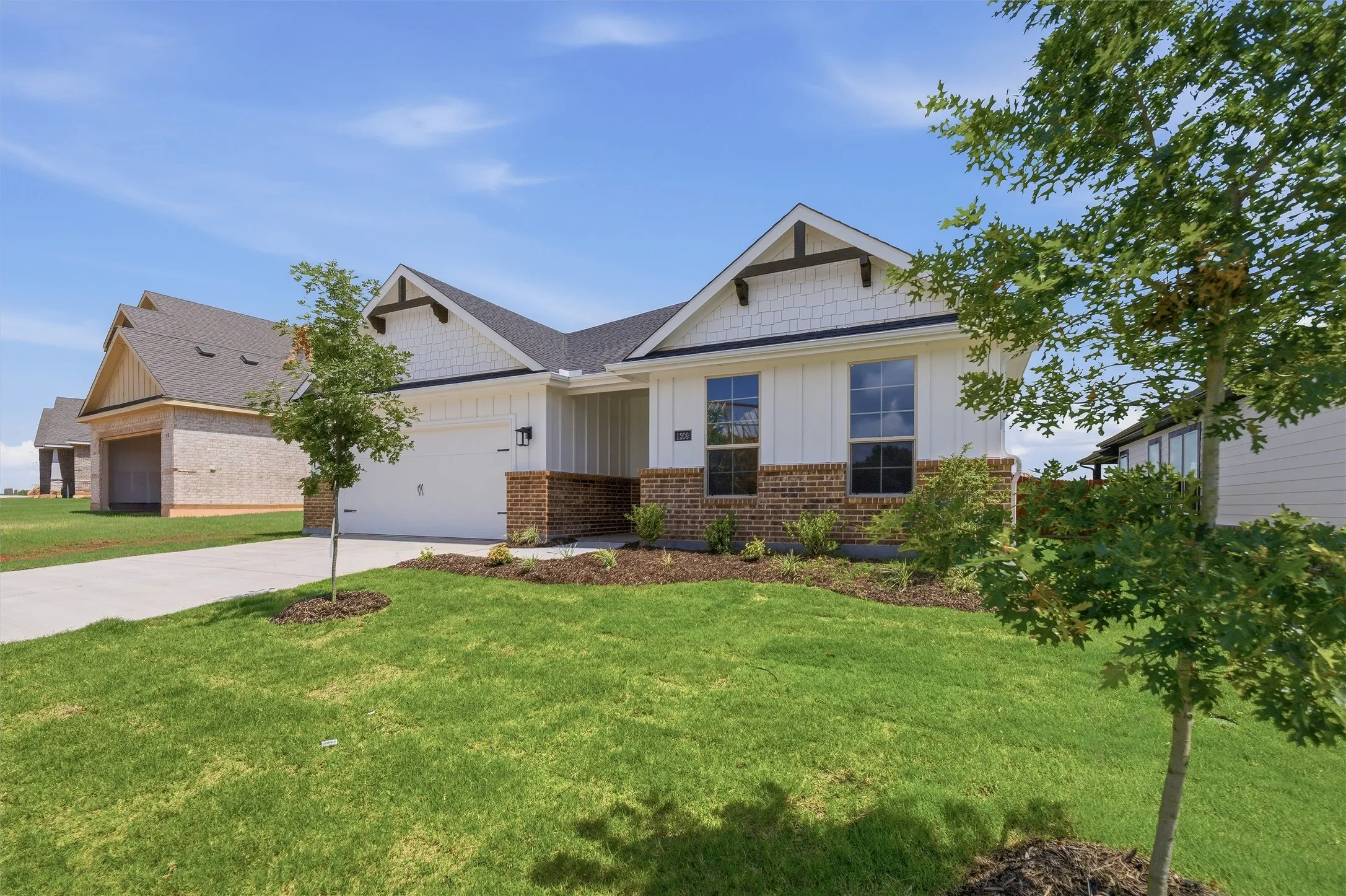 Contemporary home exterior featuring white vertical siding, brick accents, and dark trim details