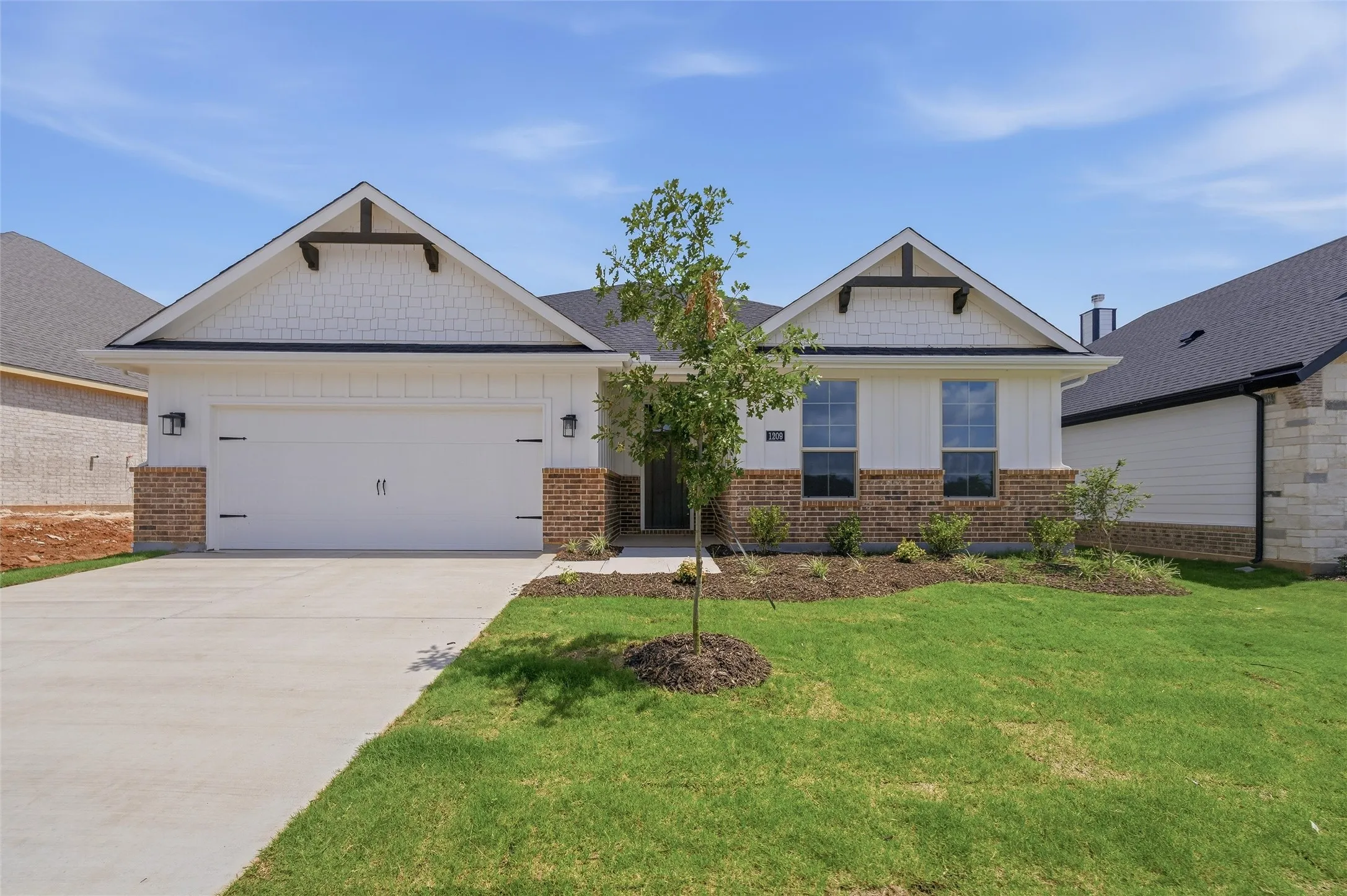 Single-story residence featuring a two-car garage, partial brick and siding exterior, a concrete driveway, and a landscaped front yard
