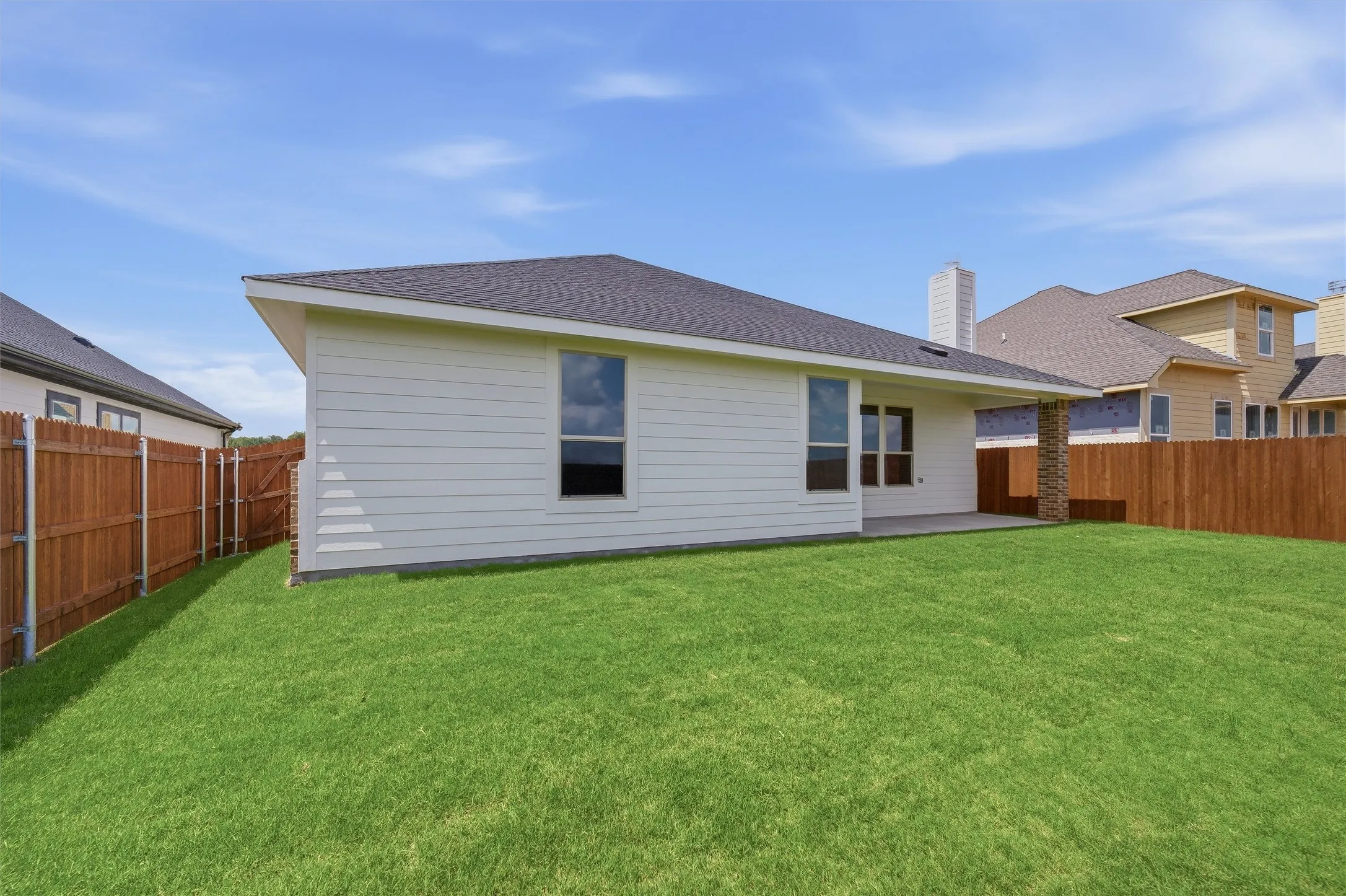 Expansive backyard featuring a manicured lawn, full wood fencing, and a concrete patio