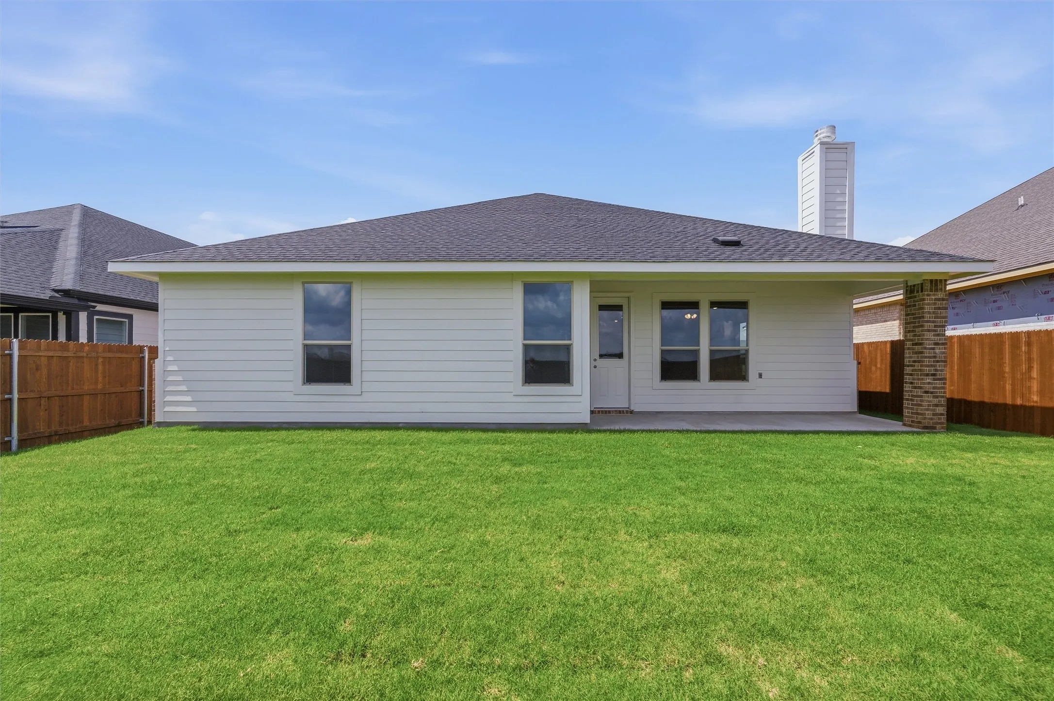 Expansive green lawn with a white horizontal siding exterior