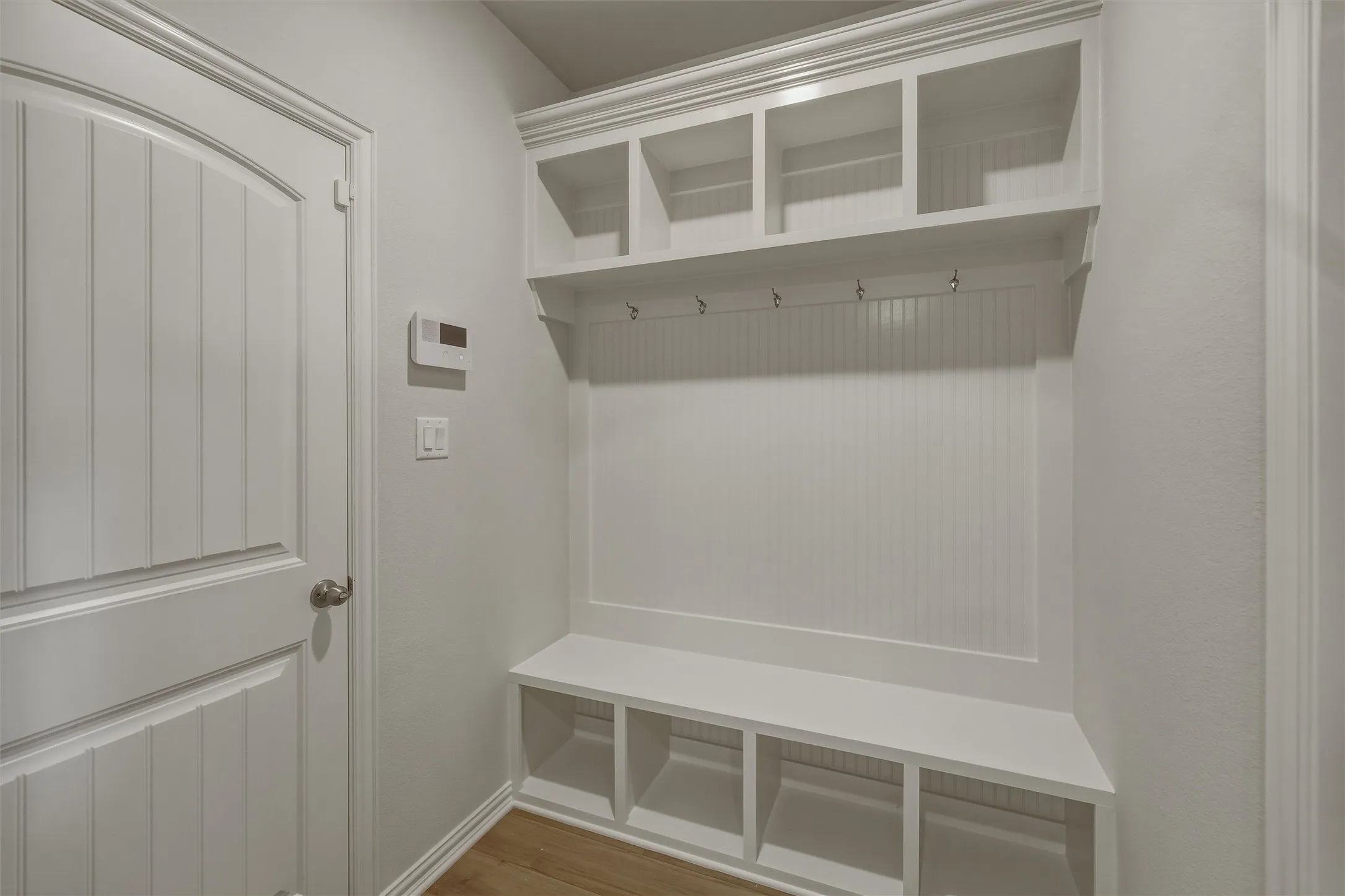 Built-in mudroom station featuring upper cubbies, coat hooks, bench seating, and lower storage compartments