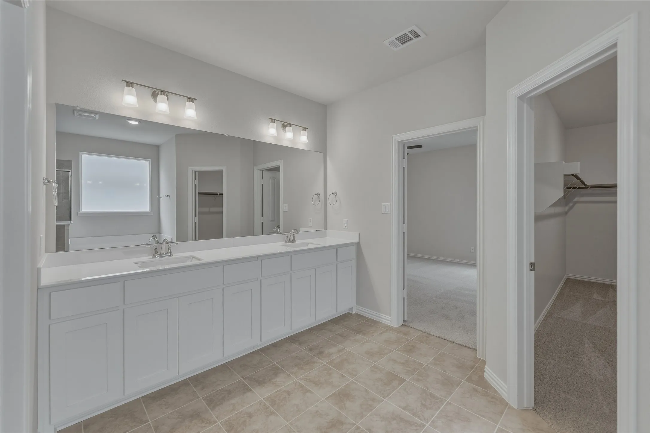Spacious bathroom featuring a dual vanity with white cabinetry, quartz-finish countertops, and two undermount sinks