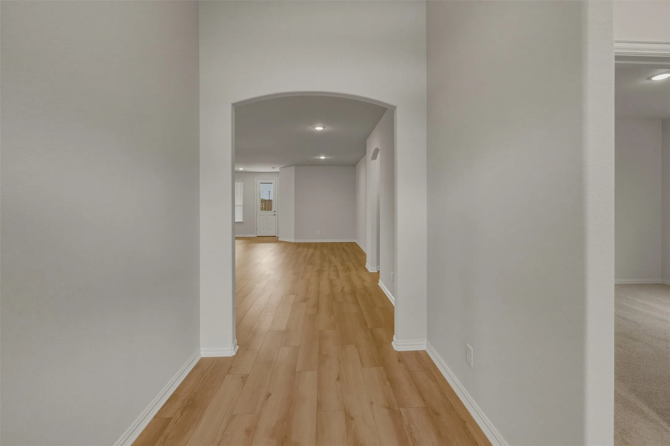 Entryway featuring wood-finish flooring, an arched doorway, recessed lighting, white baseboards, and light gray wall paint