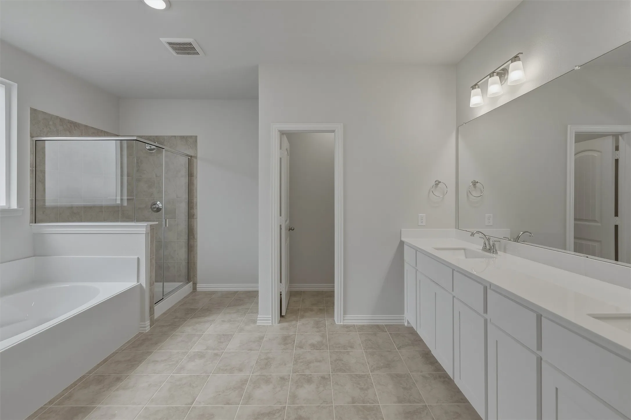 Spacious bathroom featuring a dual vanity with white cabinetry and an expansive mirror