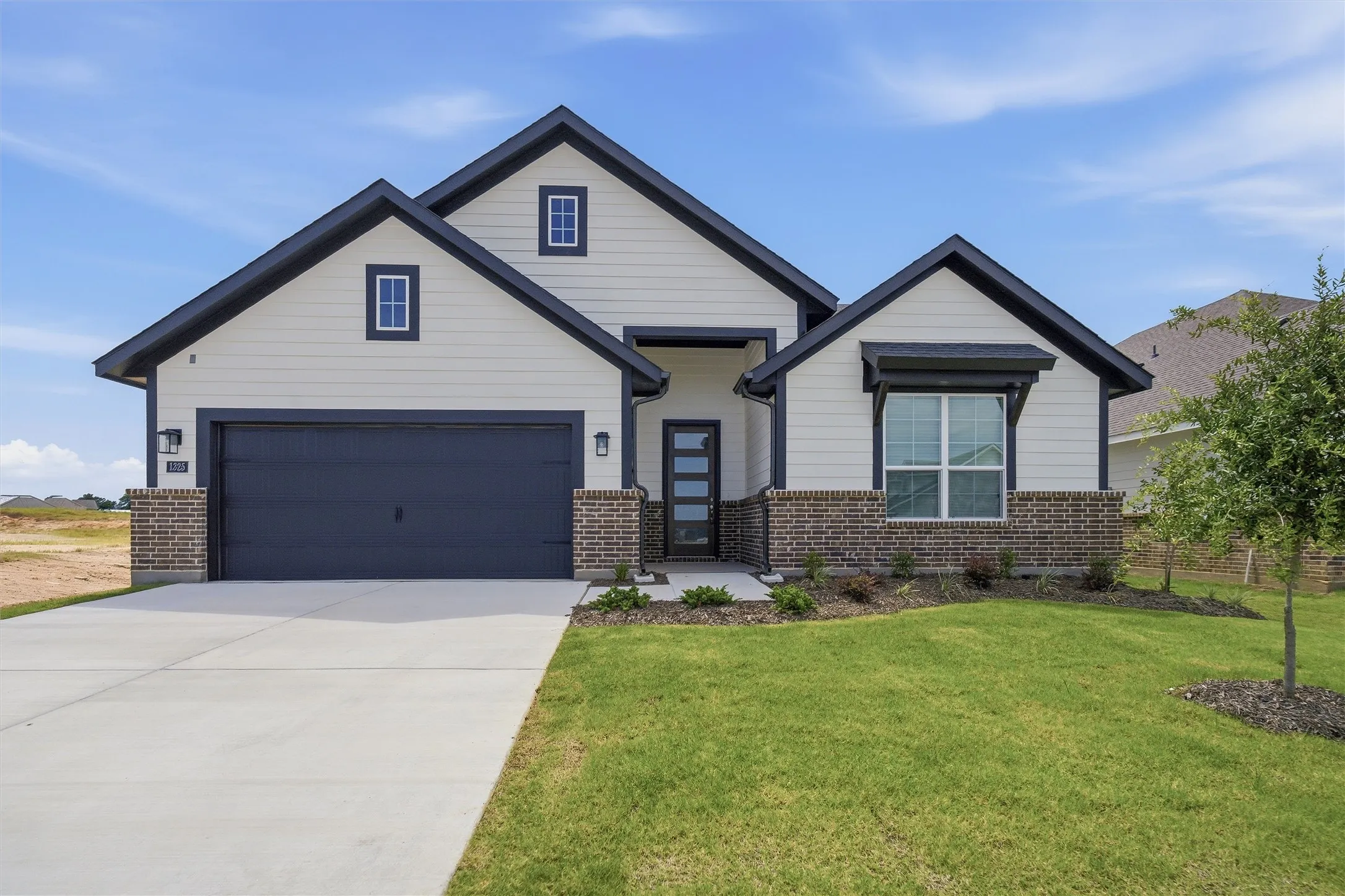 Contemporary home with a gabled roofline, dark-framed windows, brick accents, and a two-car garage