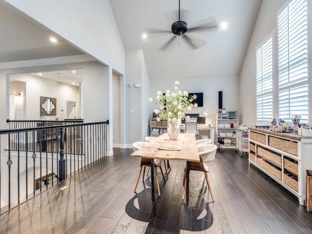Spacious upper-level loft featuring dark wood-finish flooring, vaulted ceilings, and a ceiling fan