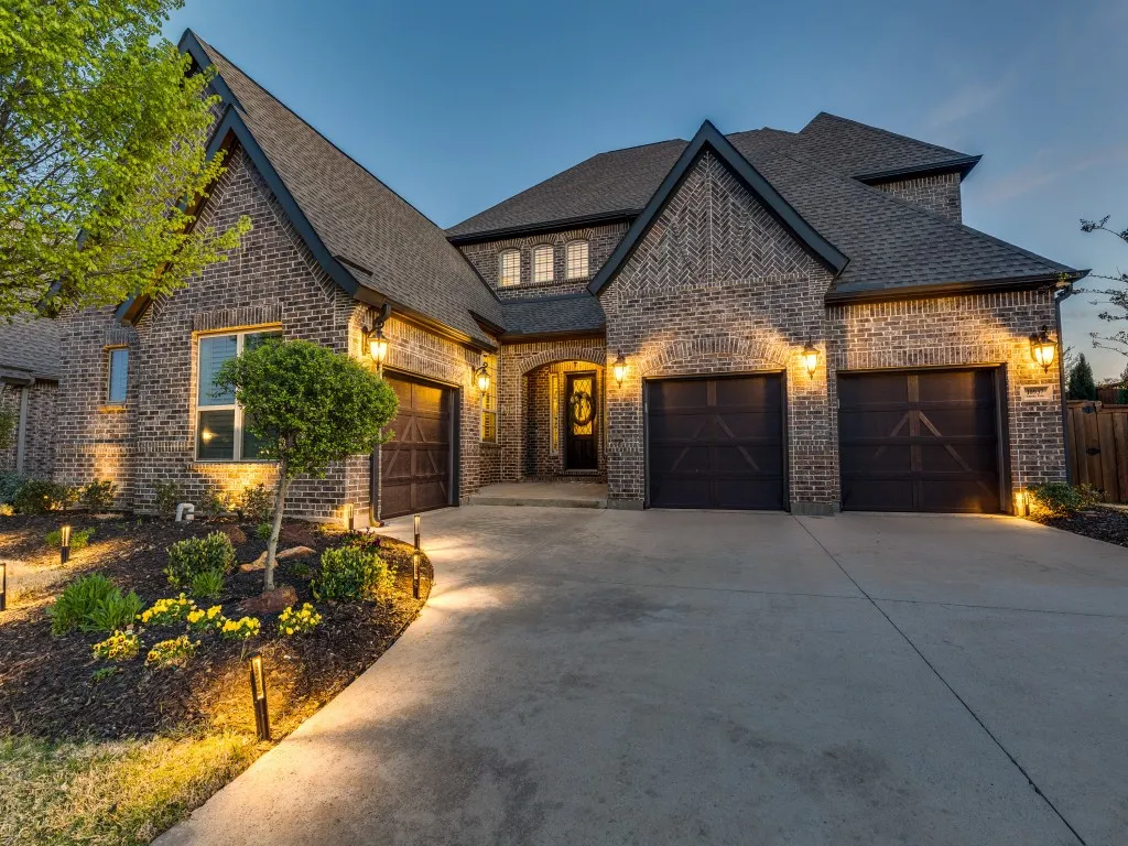 French country home with an attached garage, brick siding, and concrete driveway