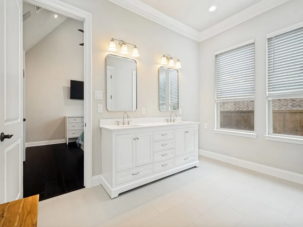 Dual white vanity with undermount sinks and brushed nickel faucets, featuring two framed mirrors and integrated lighting