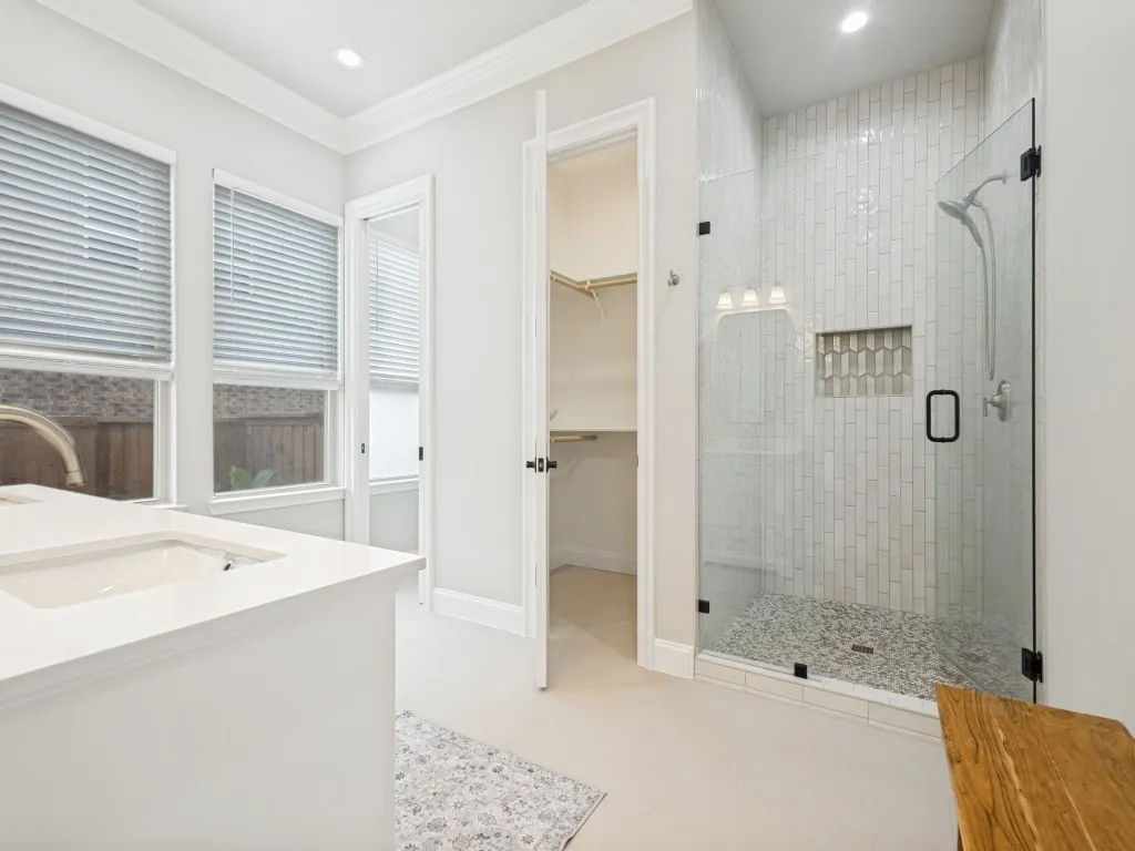 Walk-in shower with vertical subway tile, glass enclosure, and decorative tile niche