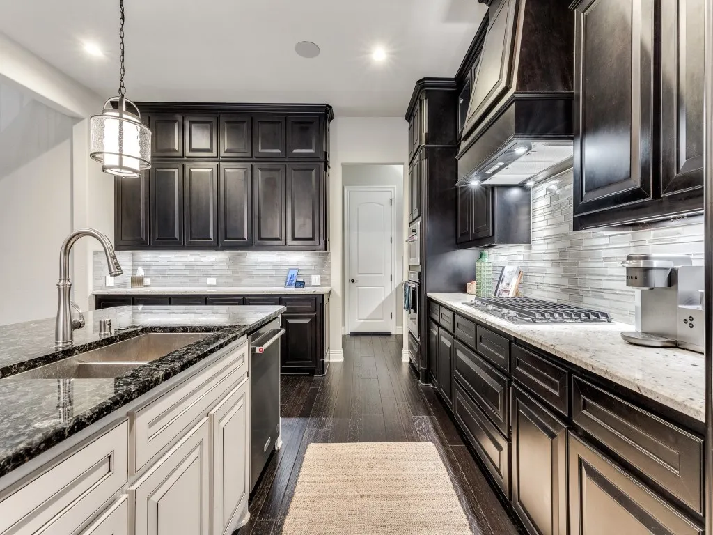 Kitchen featuring dark wood-finish cabinetry, light stone countertops, a subway tile backsplash, and stainless steel appliances