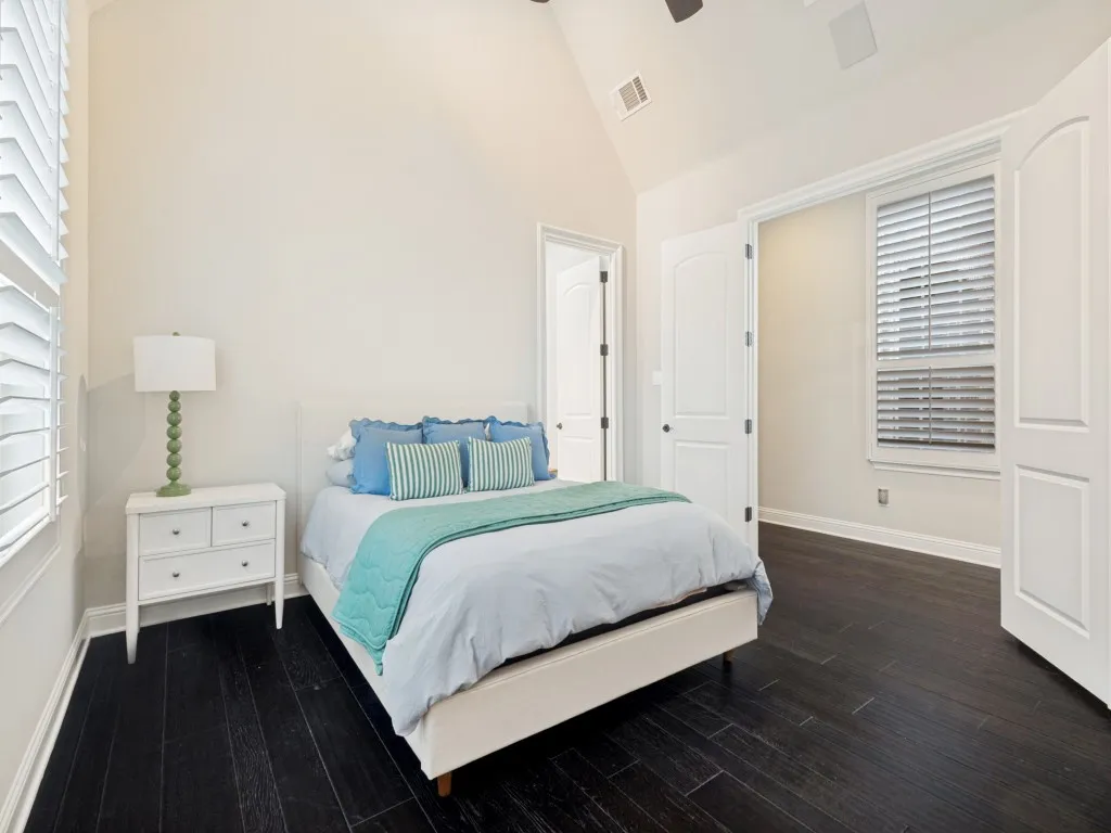 Downstairs bedroom Vaulted ceiling with a ceiling fan, dark wood-finish flooring, plantation shutters, and white paneled doors