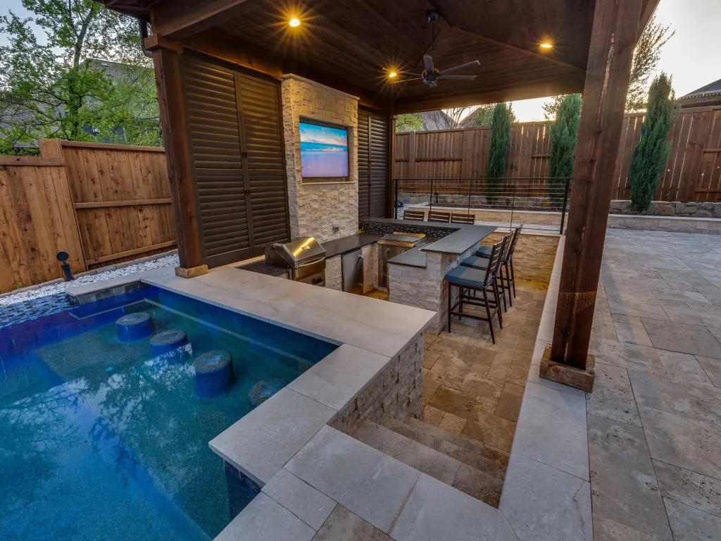 Outdoor living area featuring a covered patio with a built-in outdoor kitchen, ceiling fan, and television