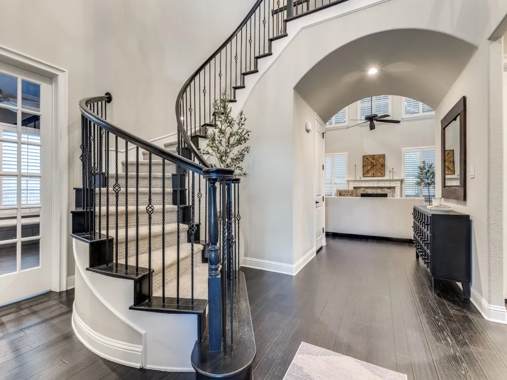 Grand entryway featuring dark wood-finish flooring and a curved staircase with wrought iron balusters