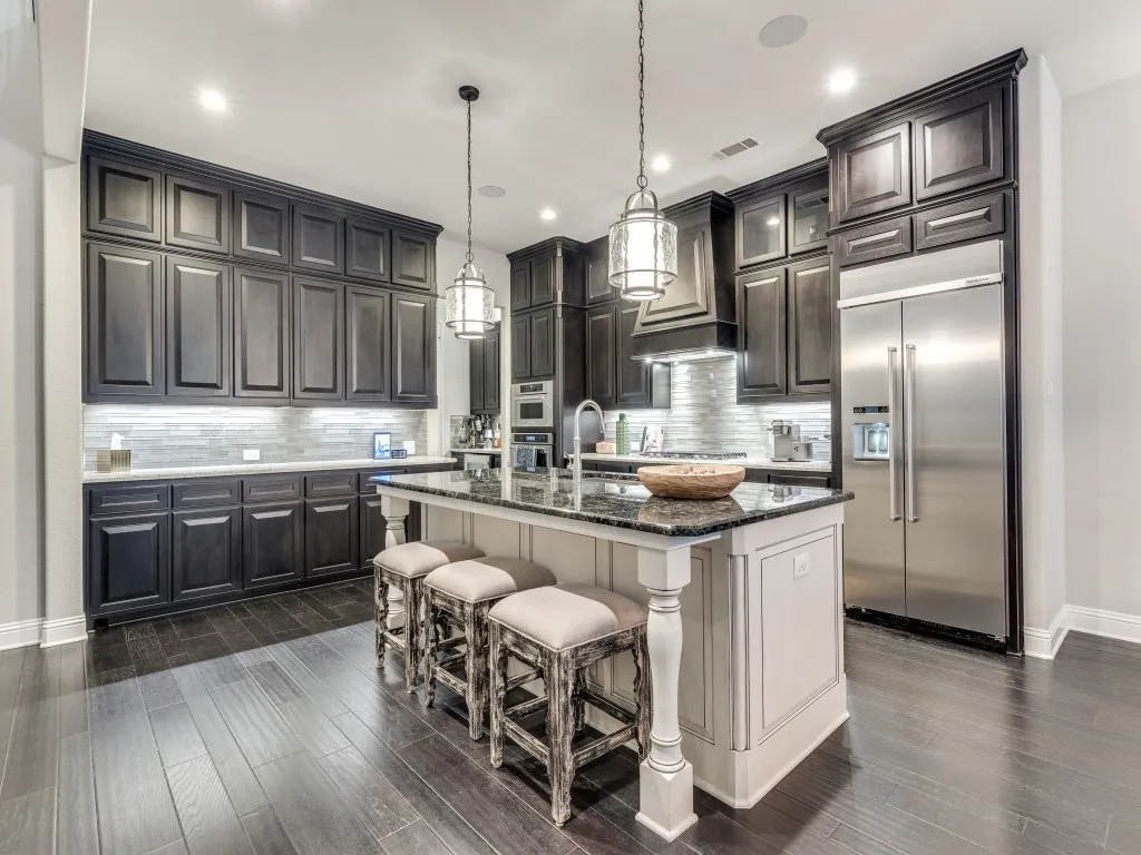 Kitchen featuring dark wood-finish cabinetry, a large kitchen island with a stone countertop, a tile backsplash, stainless steel appliances, and dark wood-finish flooring