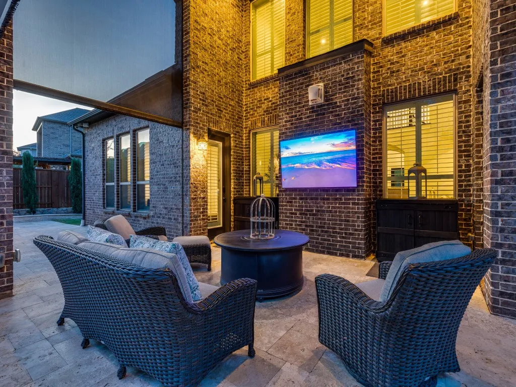 Covered patio featuring brick exterior walls, mounted outdoor television, built-in outdoor speaker, and recessed lighting
