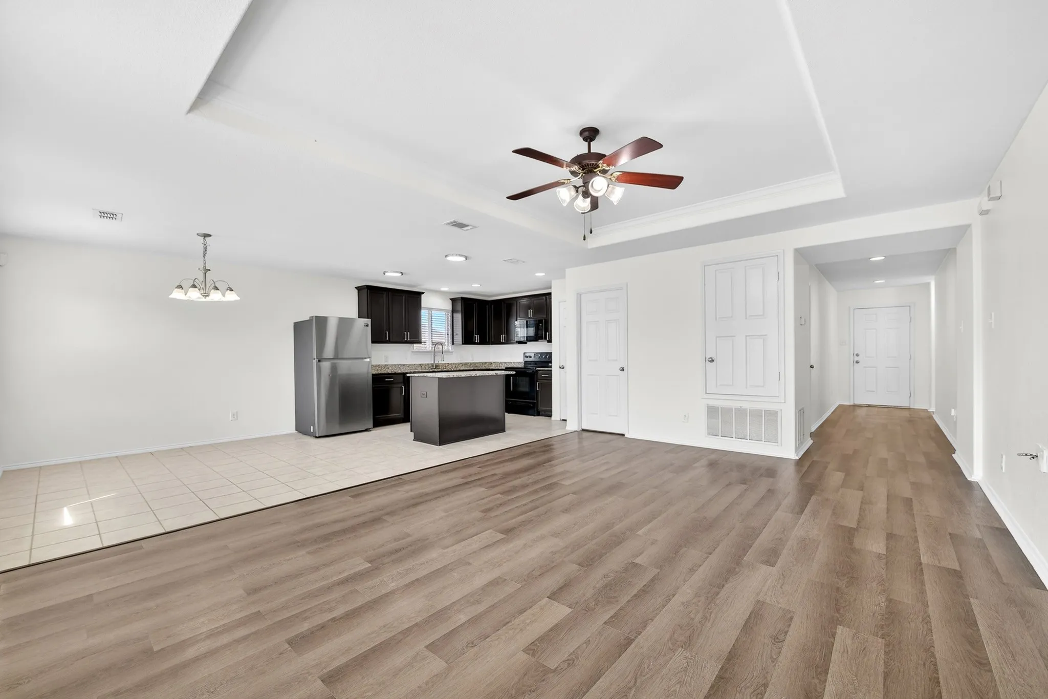 View from the Living room looking back towards the Kitchen, dining and hallway leading to the entry . Note how light and bright with tray ceiling, ceiling fan and freshly painted neutral​​‌​​​​‌​​‌‌​‌‌​​​‌‌​‌​‌​‌​​​‌​​ walls