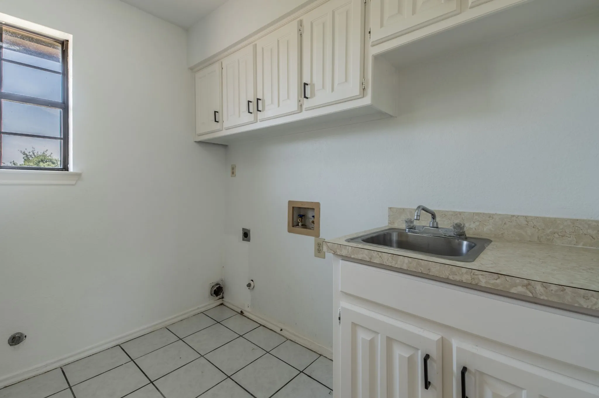 Laundry room with room for a refrigerator and/or freezer. Notice the utility sink and plenty of storage!