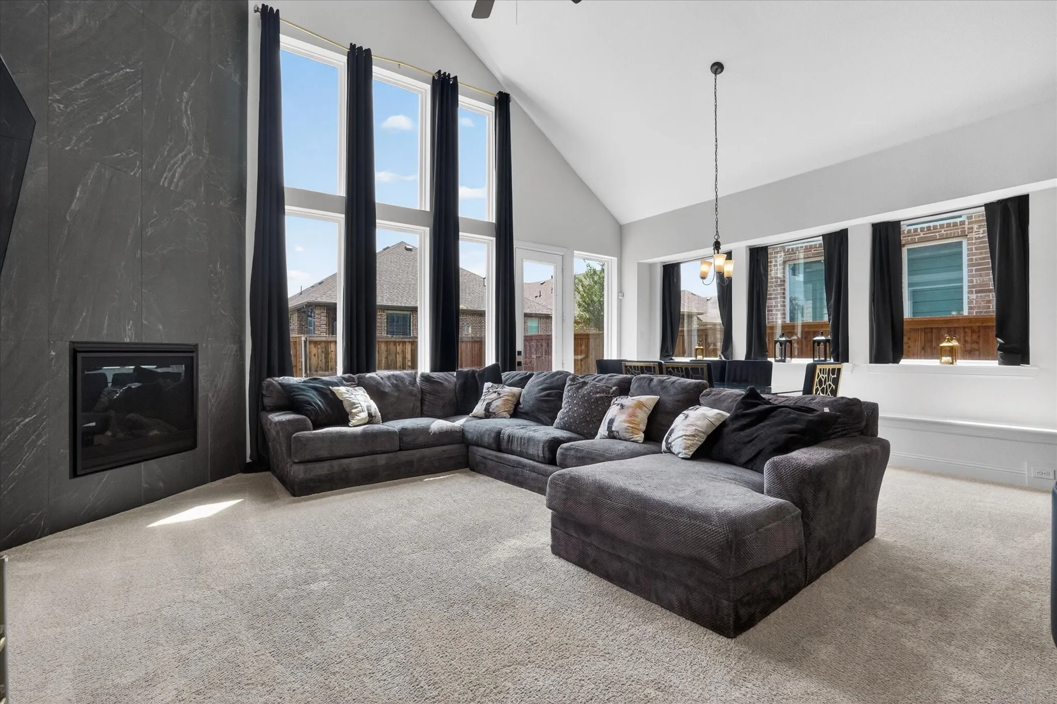 Spacious living area featuring a vaulted ceiling and light gray carpeting