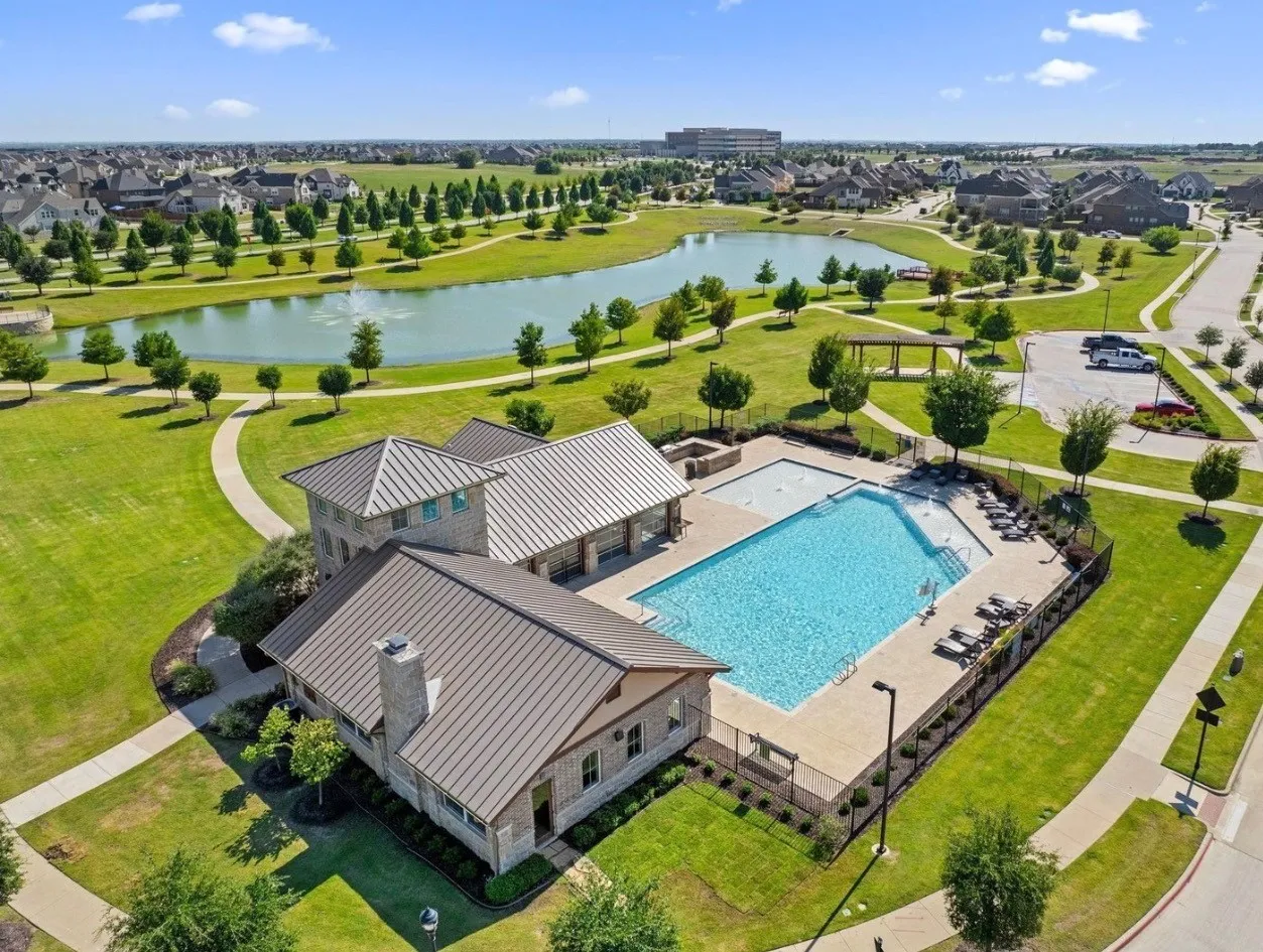Community swimming pool with surrounding amenity buildings, paved walking paths, and a water feature