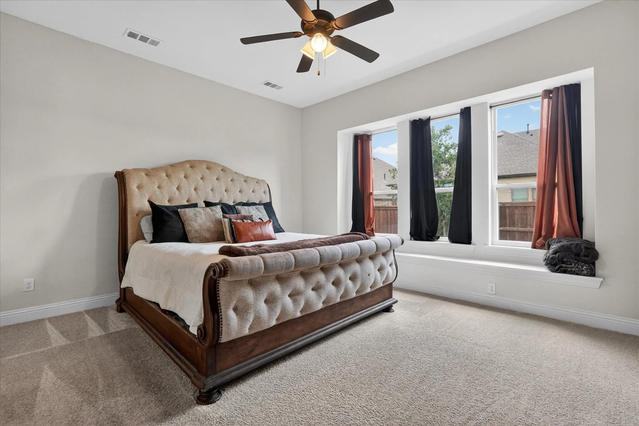 Room featuring carpet flooring, a ceiling fan with integrated lighting, three windows with white trim, and a window ledge