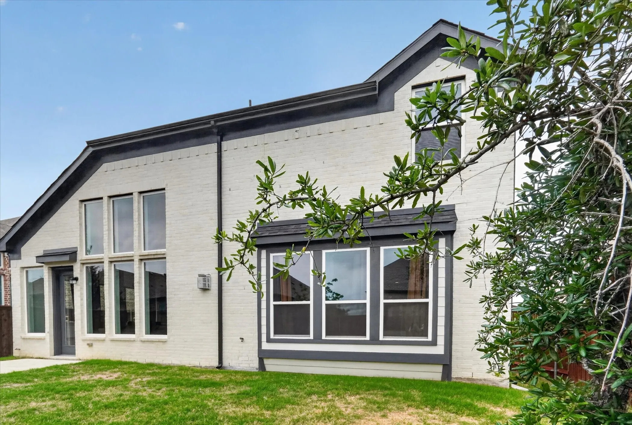 Rear exterior featuring light-colored brick with dark trim accents