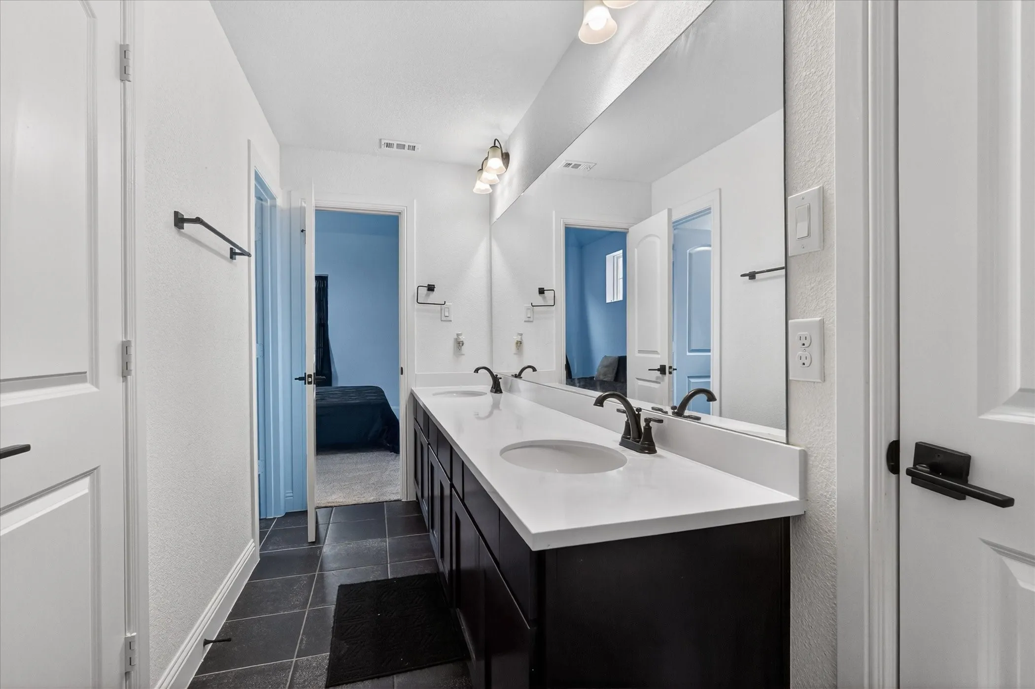 Jack & Jill bathroom featuring a double vanity with white countertops, dark cabinets