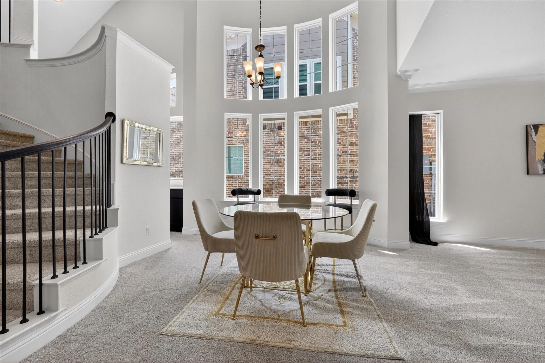 Two-story entry featuring a curved staircase with black wrought iron spindles and a large arched window array