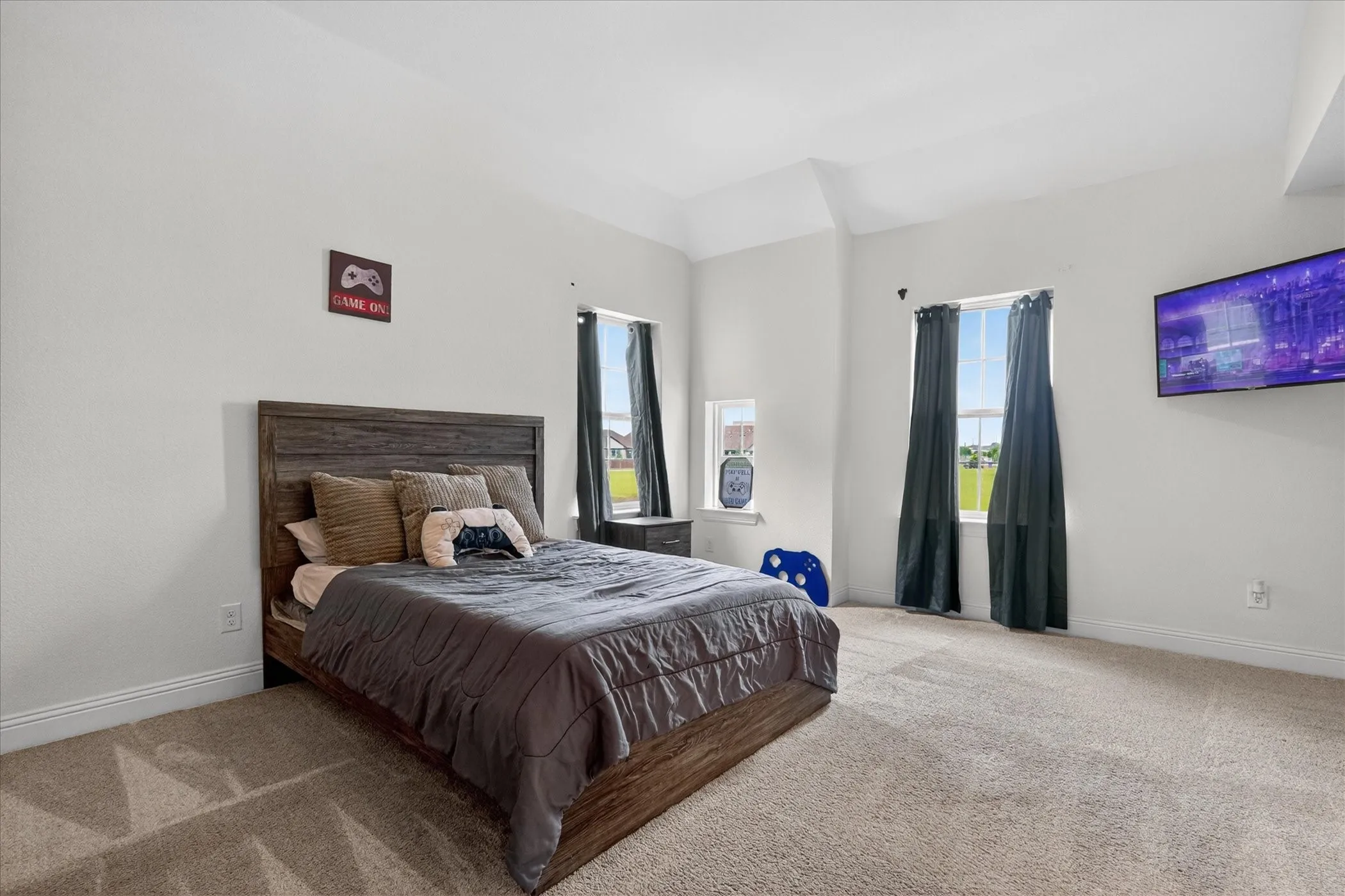 Generously sized bedroom featuring soaring vaulted ceilings, abundant natural light, and plenty of space for a sitting area or study nook.