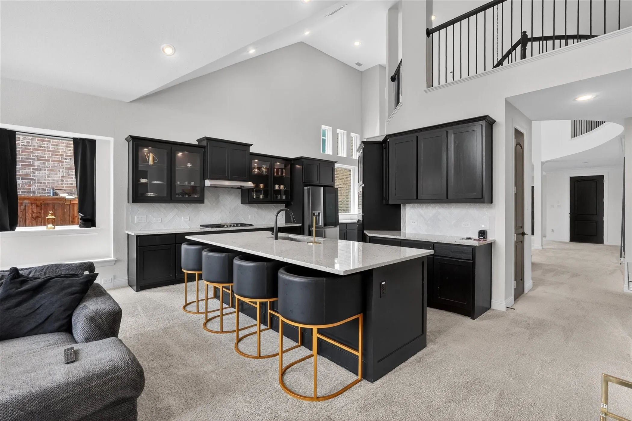 Gourmet kitchen featuring black cabinetry, light stone countertops, a tile backsplash, and a large island with seating