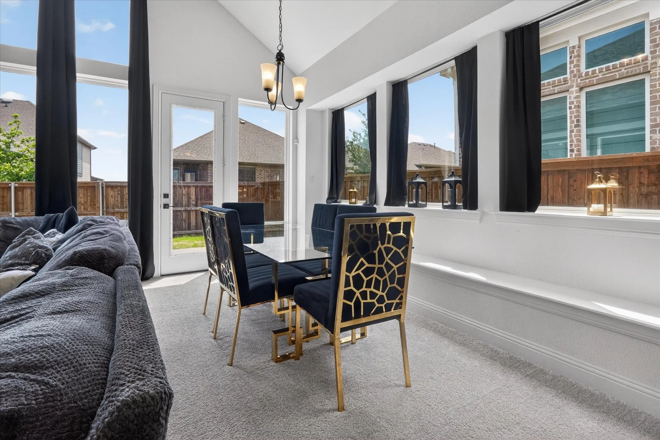Dining area with vaulted ceilings, large windows, an exterior door, and a three-light chandelier