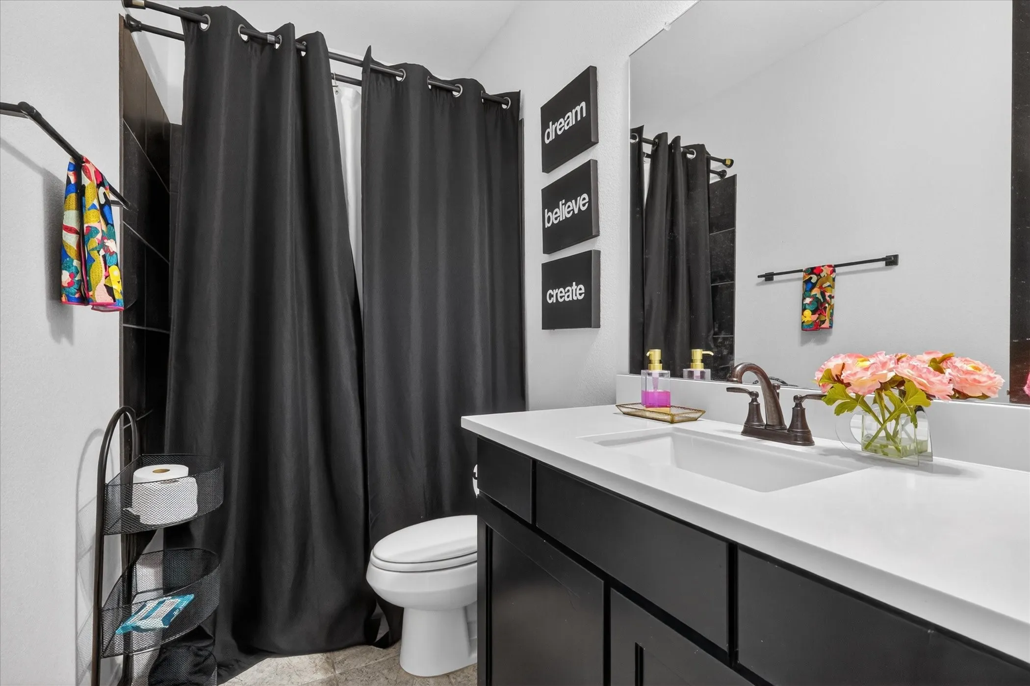 Modern bathroom featuring a single vanity with a white countertop and dark cabinetry