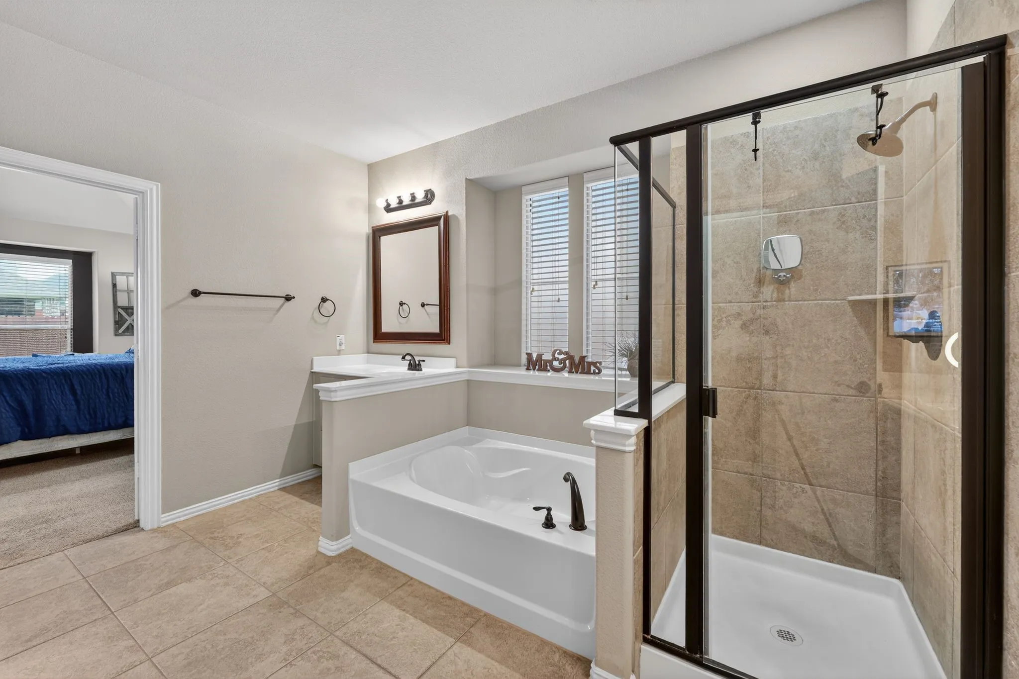 Bathroom featuring a walk-in shower with tile surround, built-in tub, single vanity with countertop, and tile flooring