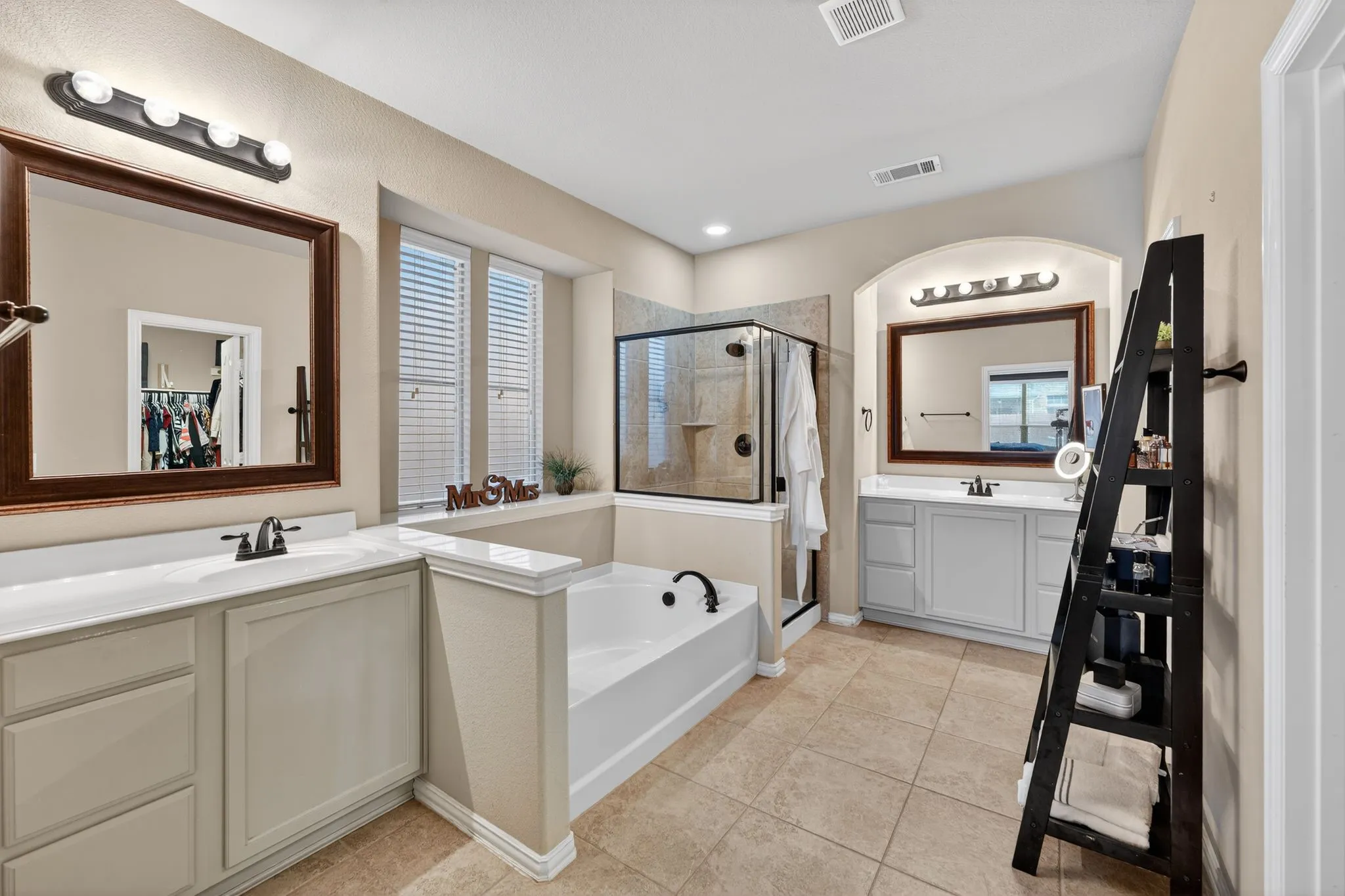 Spacious bathroom featuring dual vanities with integrated sinks, a built-in soaking tub, and a separate glass-enclosed shower