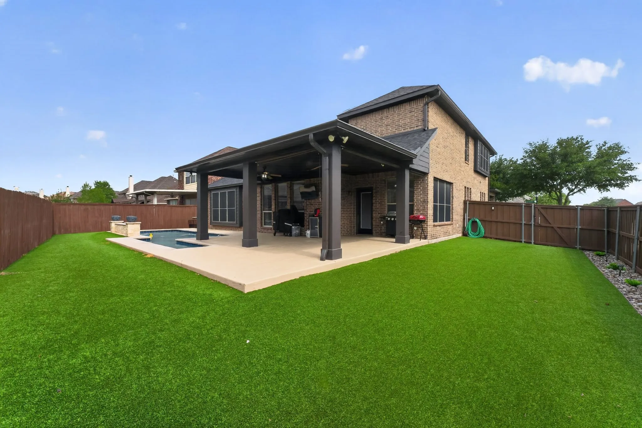 Expansive turf lawn with a covered patio and swimming pool.