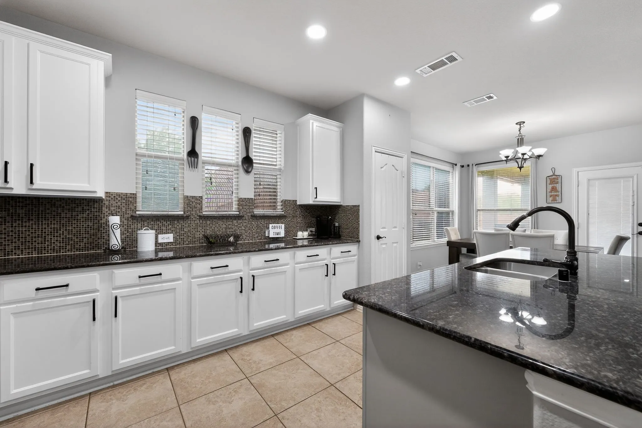 Kitchen featuring white cabinetry, dark stone countertops, and a mosaic tile backsplash