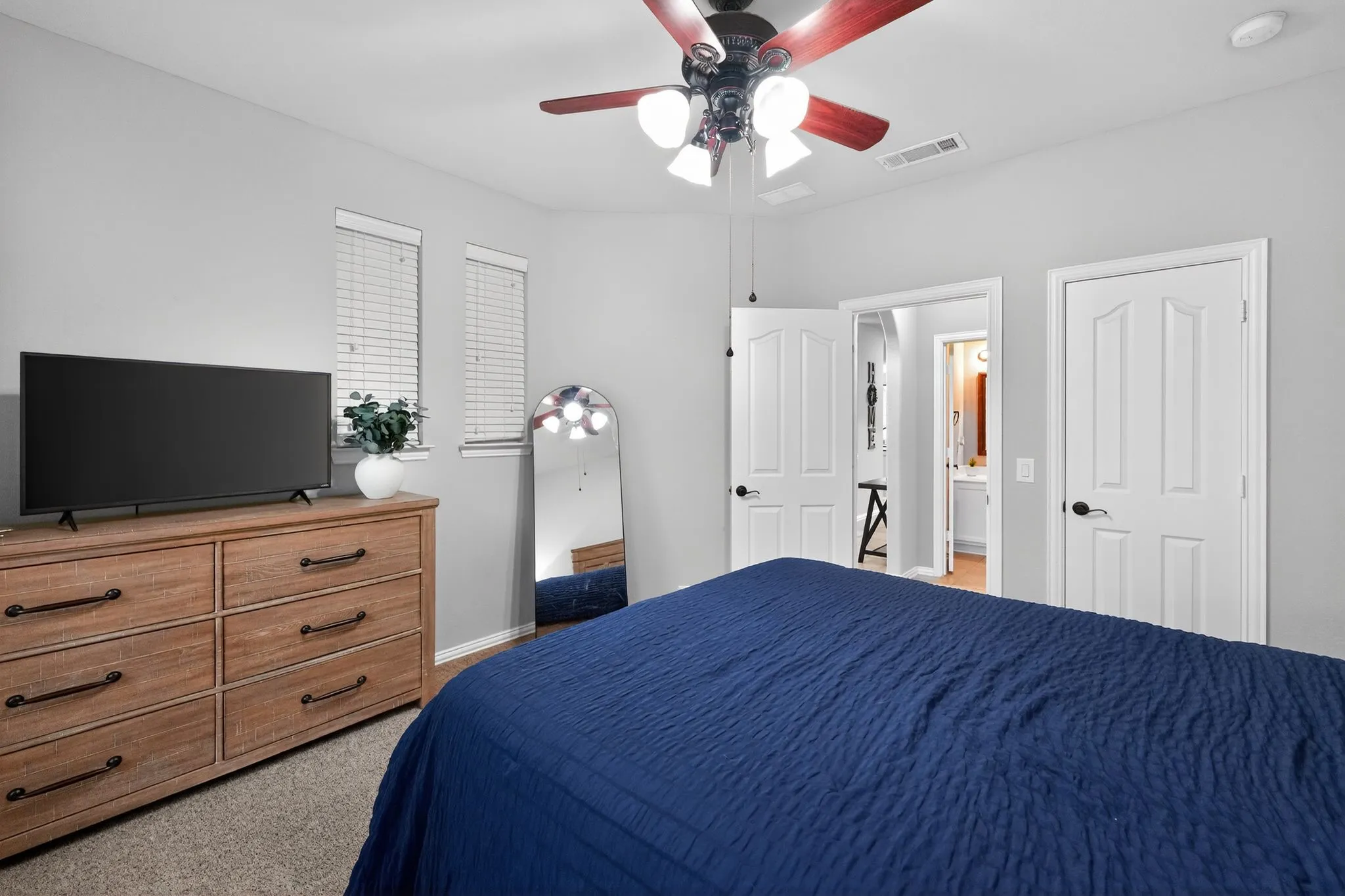 Downstairs - Bedroom #2 featuring light gray walls, carpet flooring, two windows with blinds, and a ceiling fan with integrated lighting