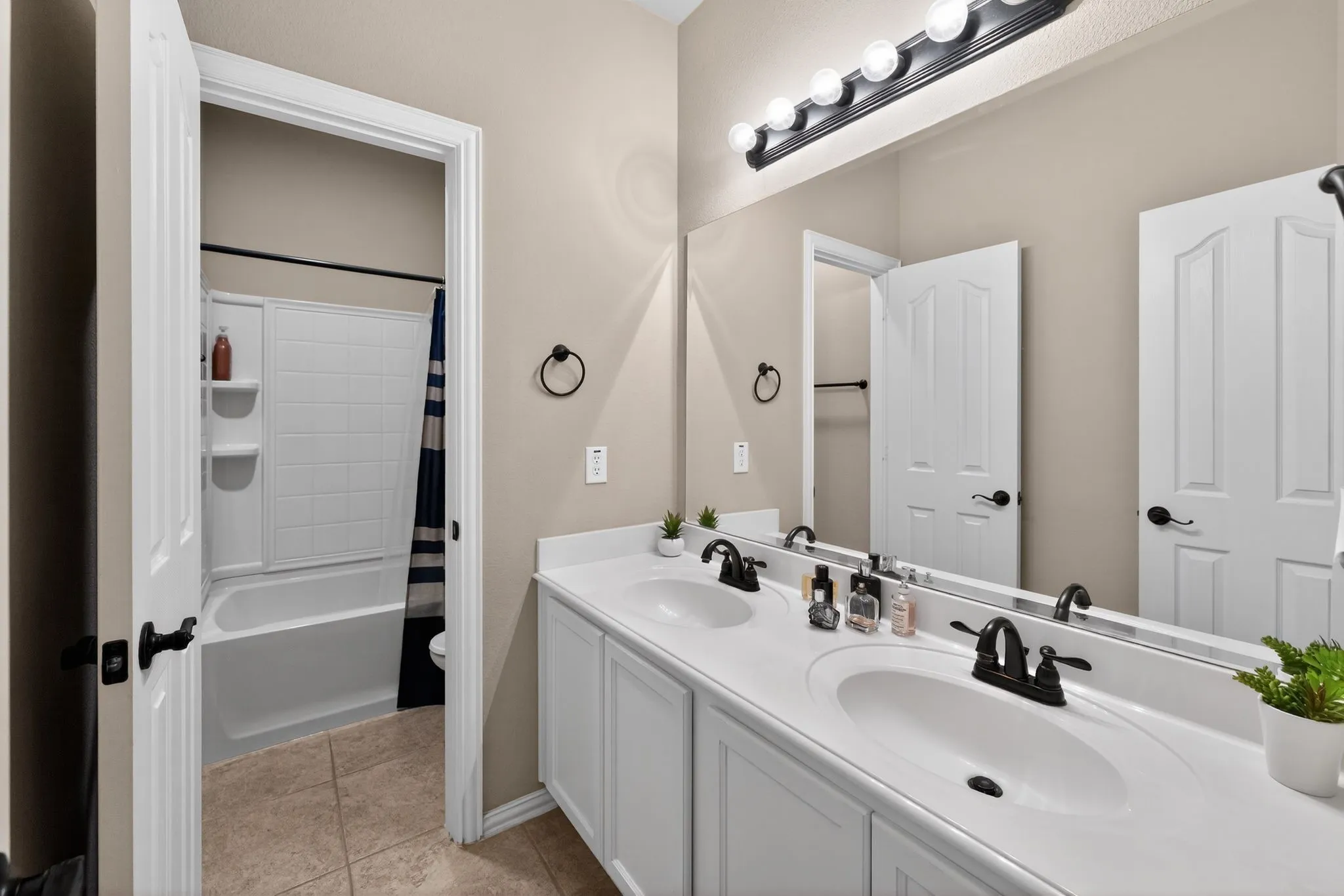 Upstairs Bathroom - Double vanity with integrated sinks, white cabinetry, matte black fixtures, and a large wall-mounted mirror