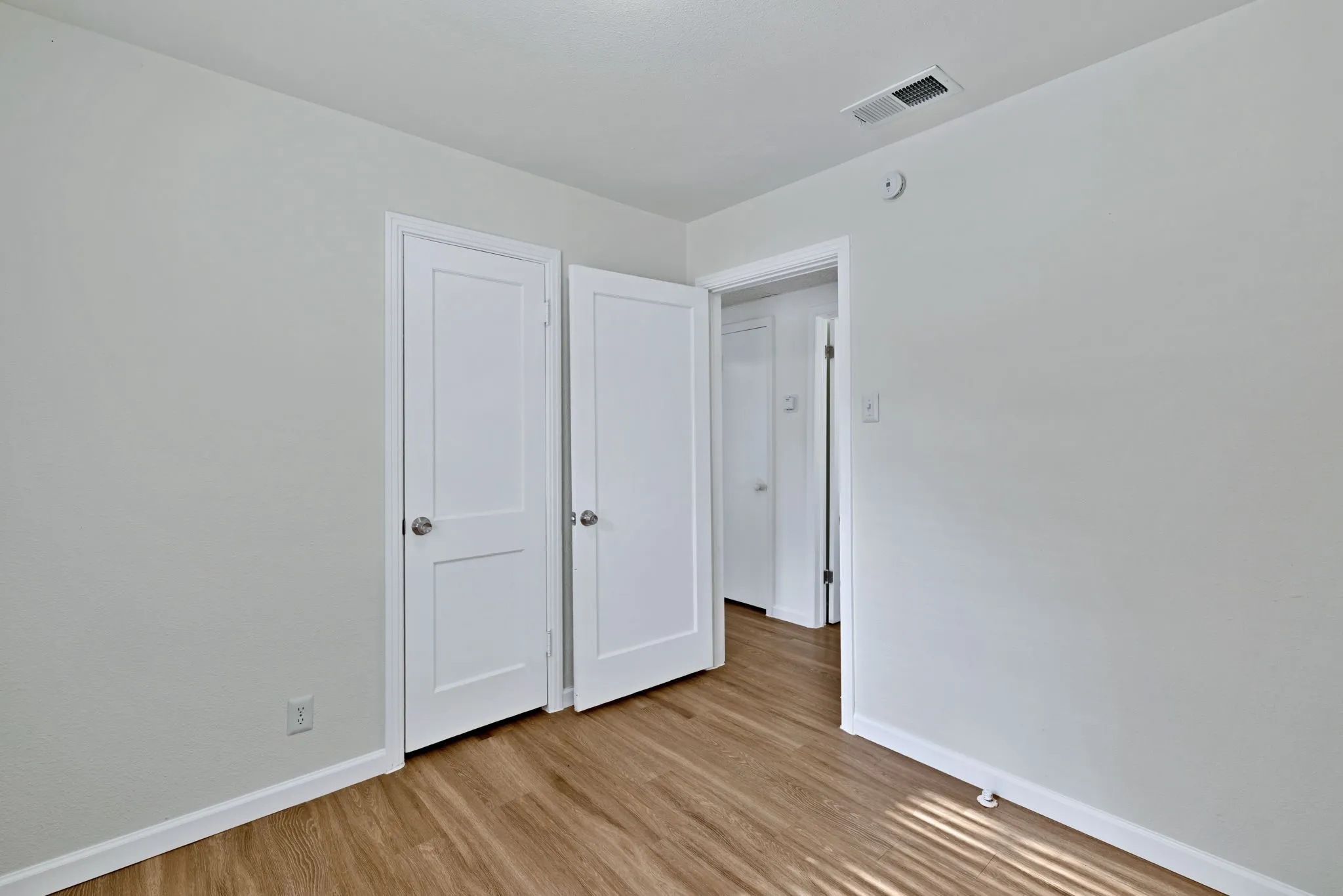 Light-filled interior featuring wood-finish flooring, white baseboards, and neutral wall paint