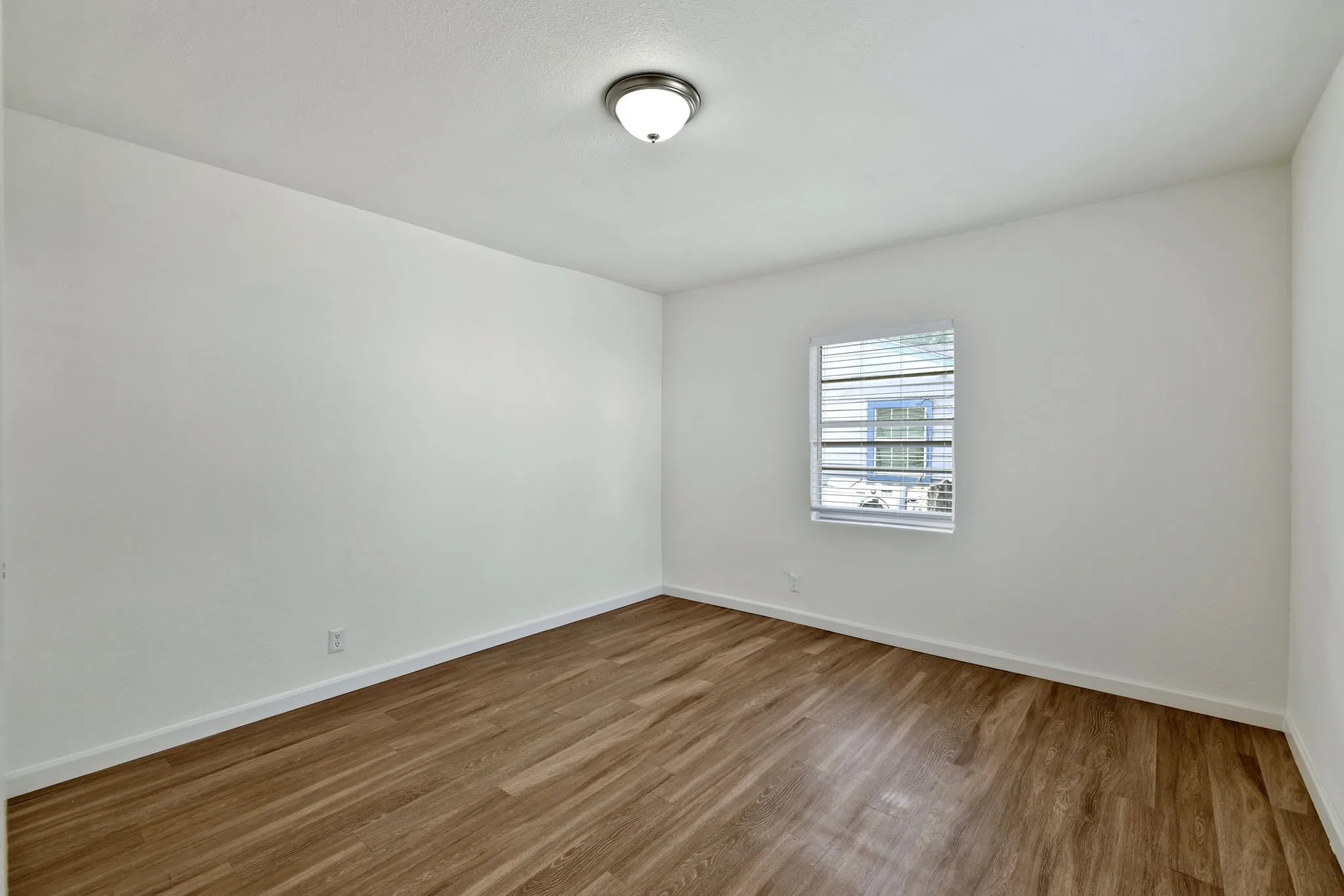 Interior room featuring wood-finish flooring, white baseboards, and neutral wall paint