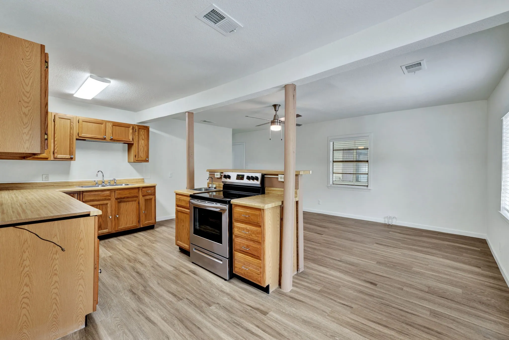 Kitchen featuring wood cabinetry, laminate countertops, stainless steel range with overhead microwave, and a double basin sink