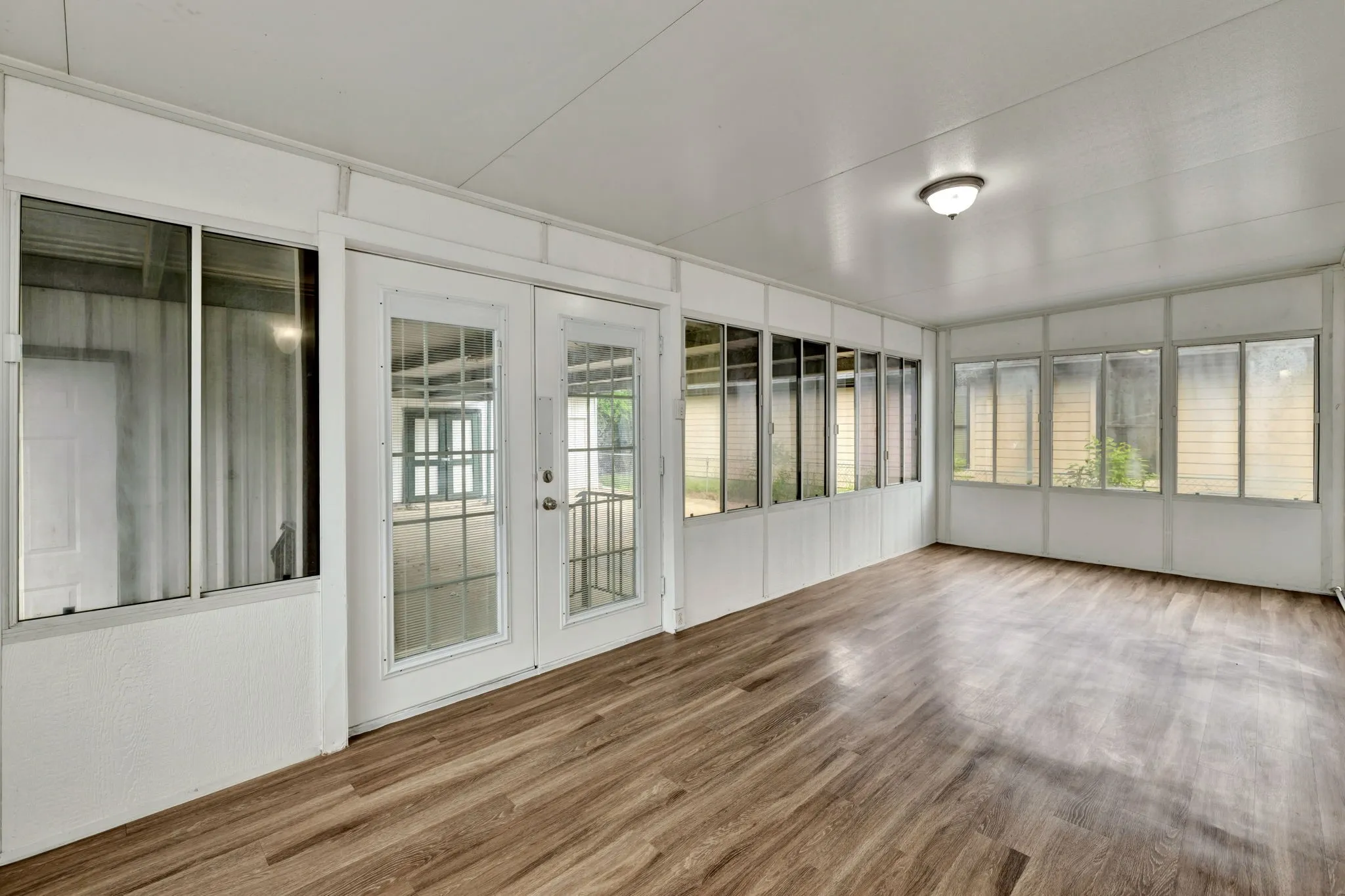 Enclosed patio featuring wood-finish flooring, white paneled walls, and multiple windows
