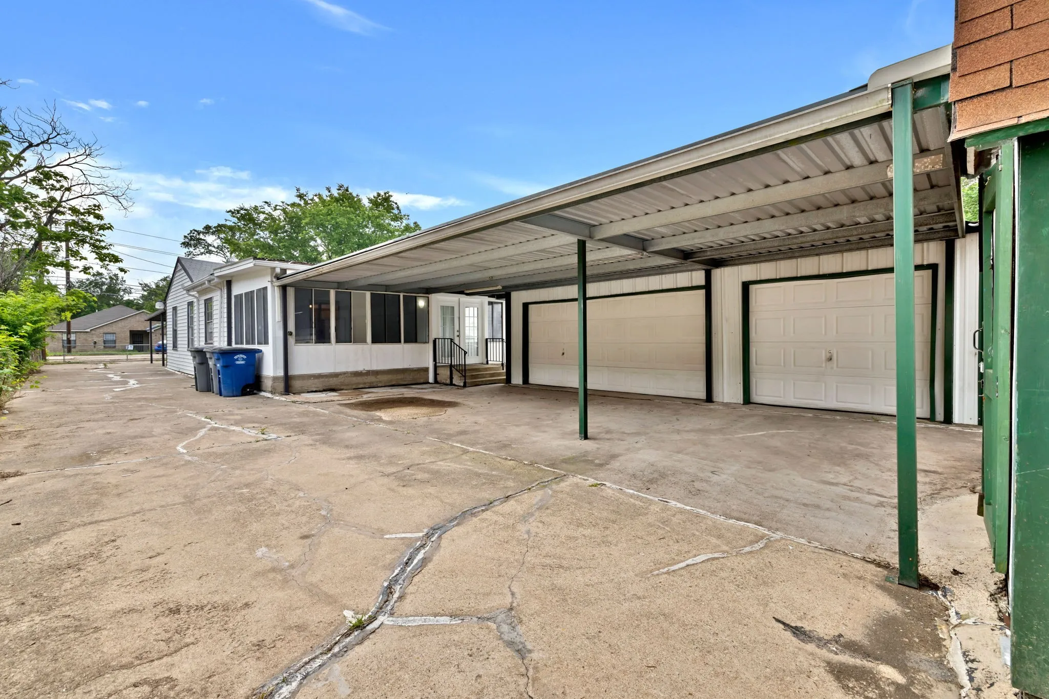 Rear exterior featuring a metal carport structure and two white garage doors