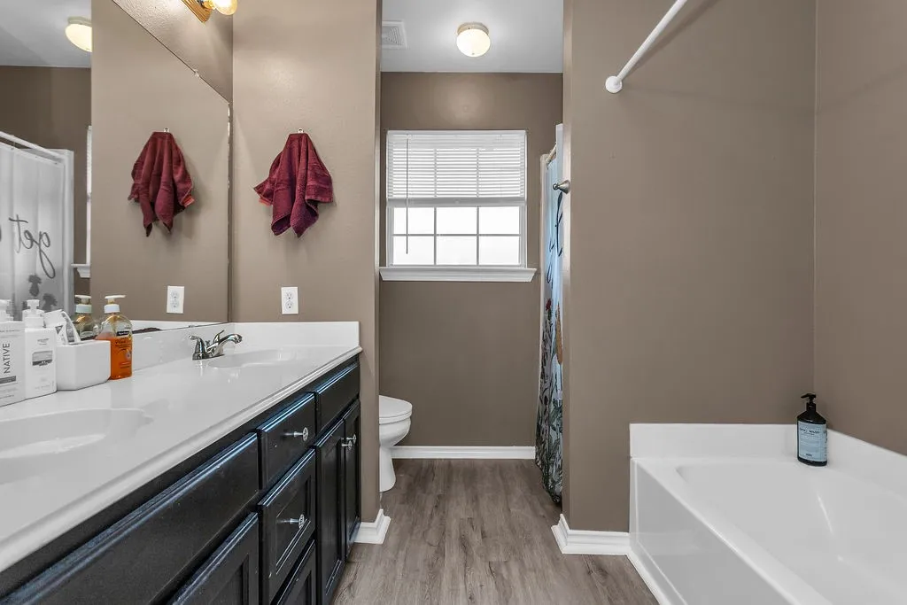 Bathroom featuring a dual-sink vanity with dark cabinetry, integrated white countertops, and chrome fixtures