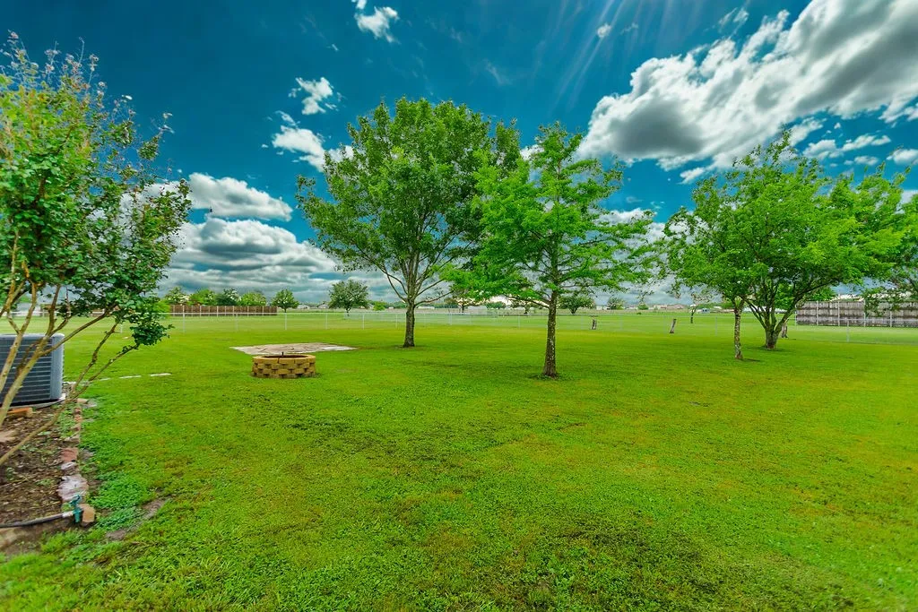 Expansive green lawn featuring a built-in stone fire pit