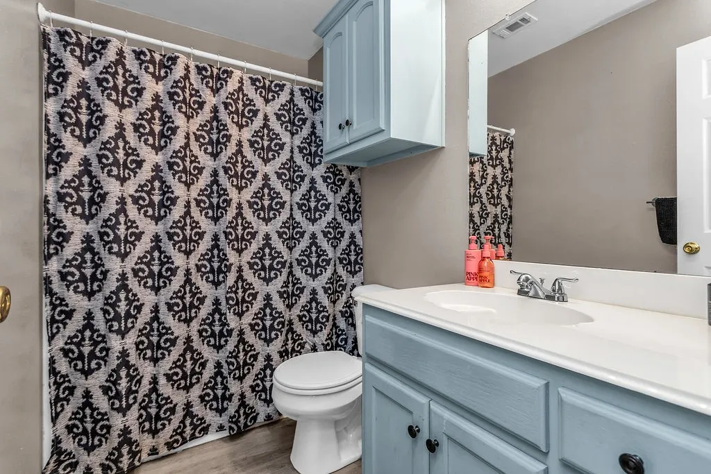 Bathroom featuring a light blue vanity with black hardware, an oval undermount sink, and a framed mirror